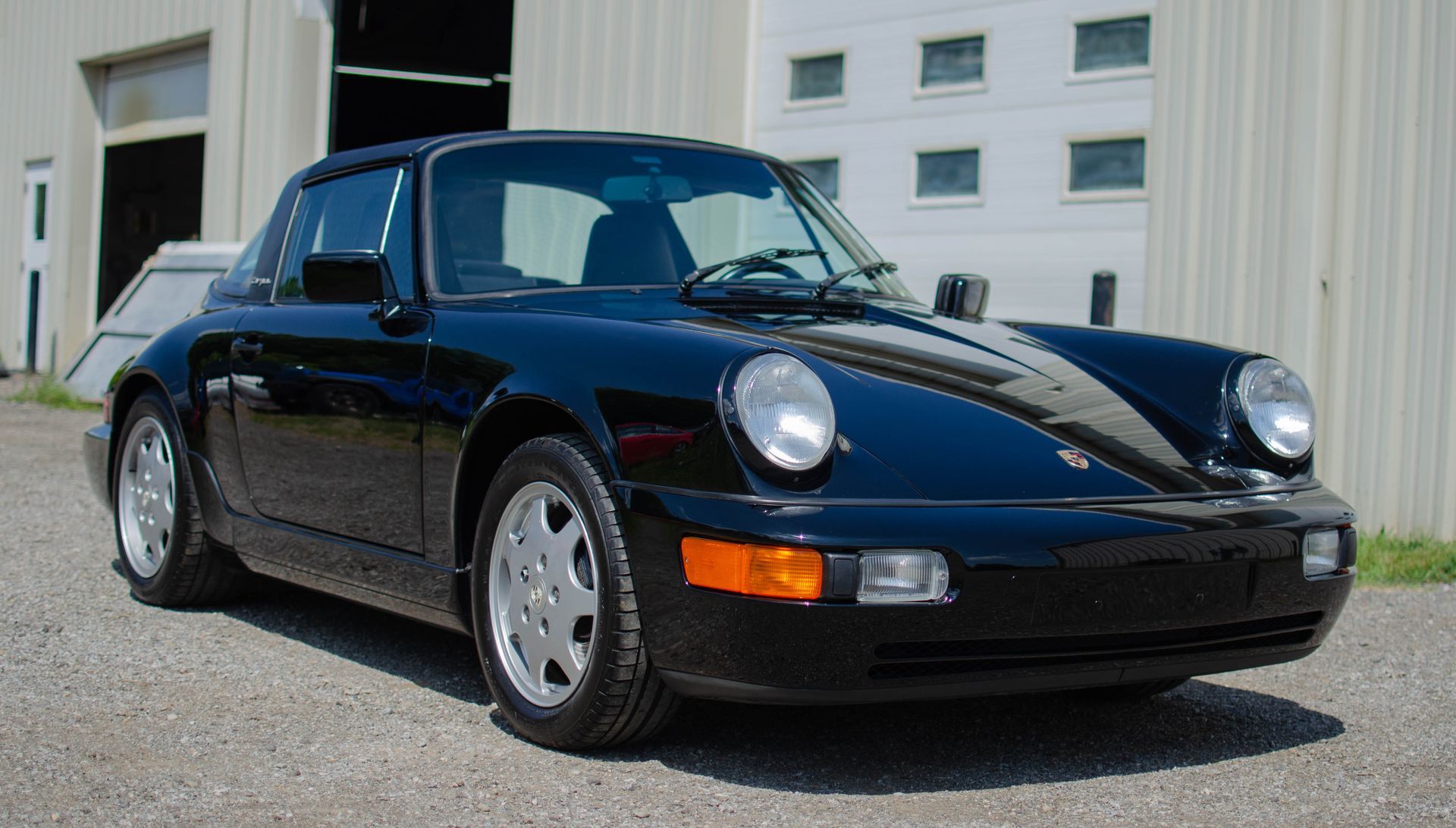 Black classic Porsche 911 parked outside a white industrial building