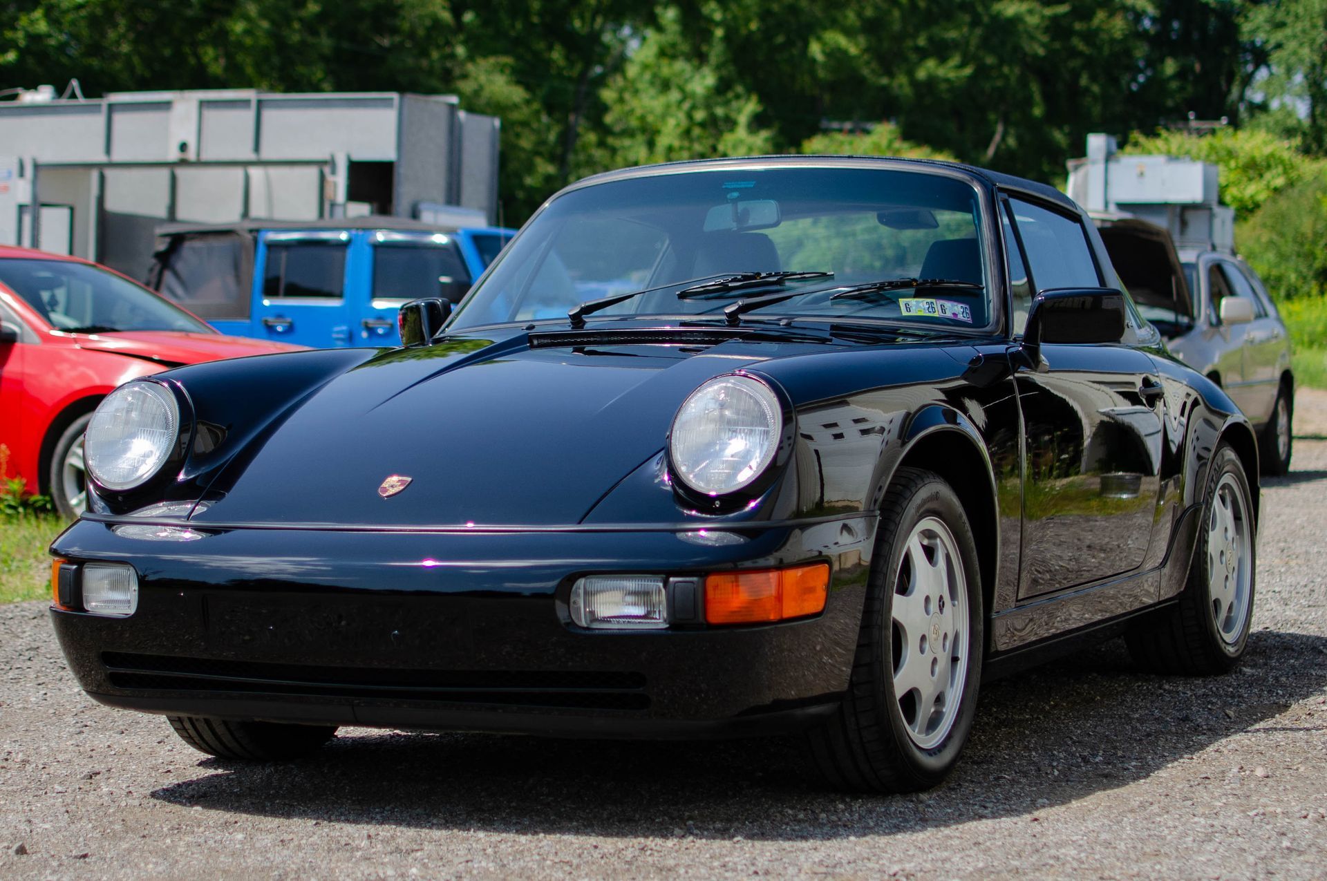 Black Porsche 911 parked outdoors with other cars in the background