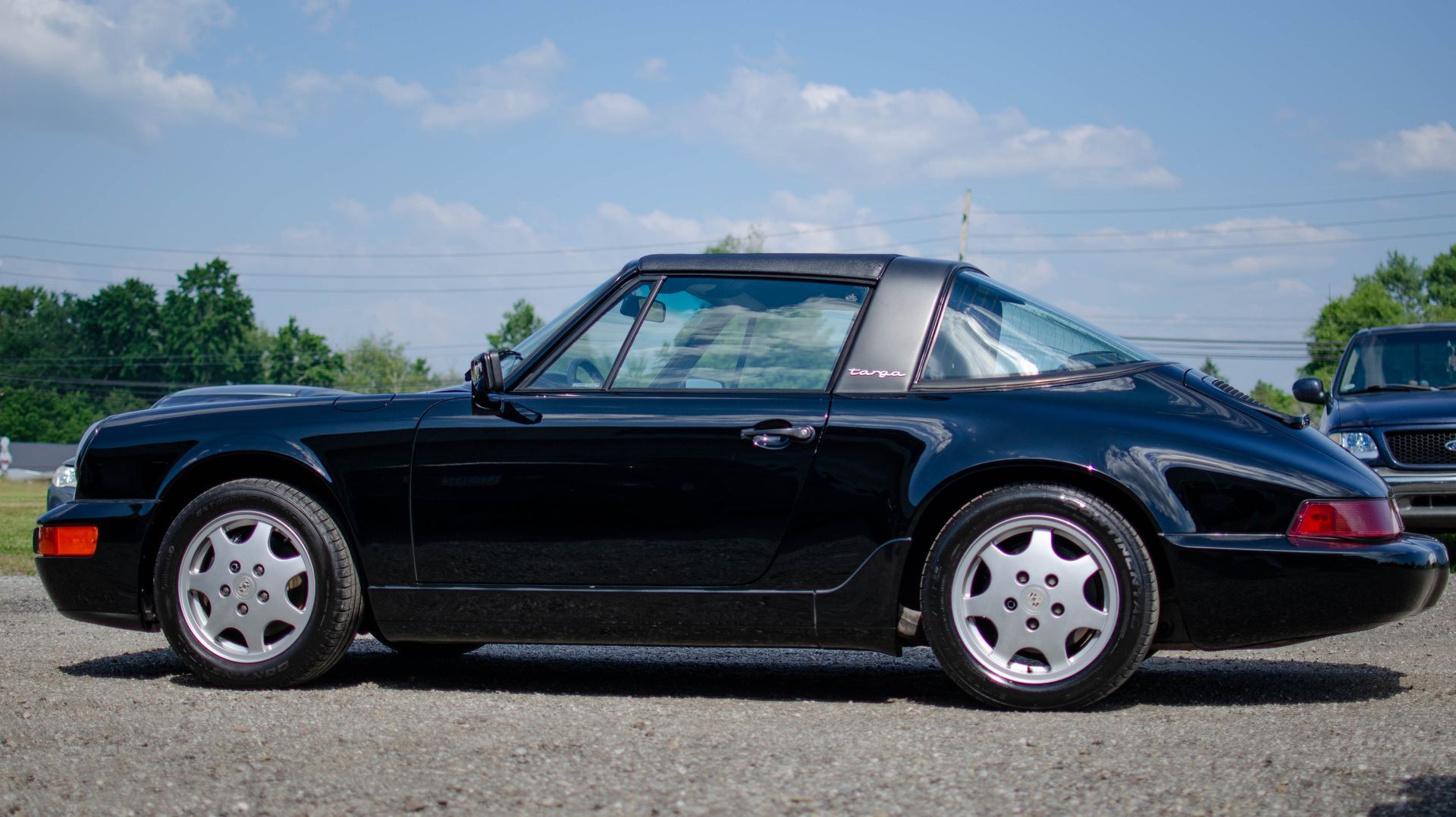 Black vintage Porsche 911 parked outdoors on a sunny day, side view