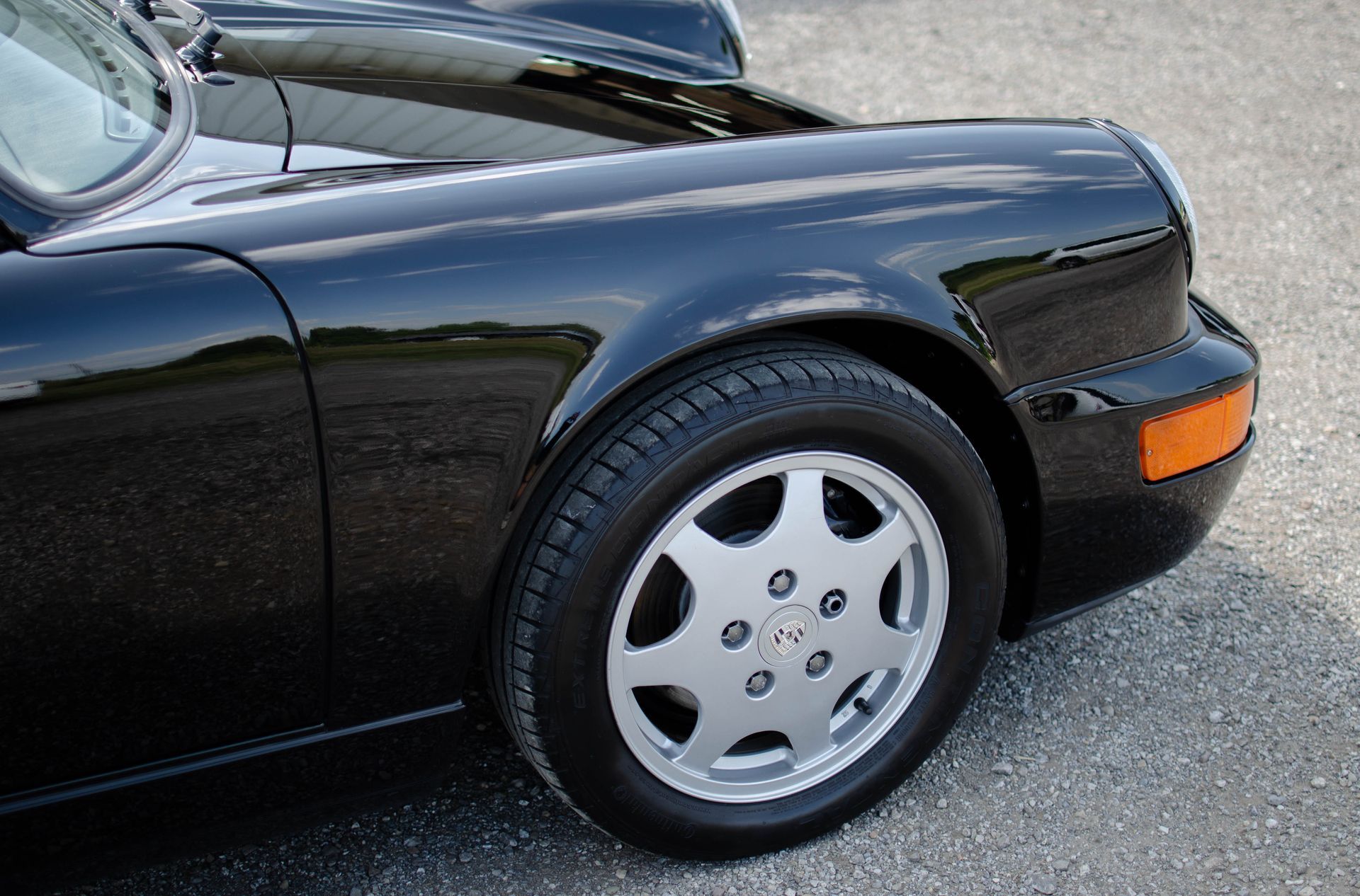 Close-up of a black sports car’s front wheel and fender on pavement
