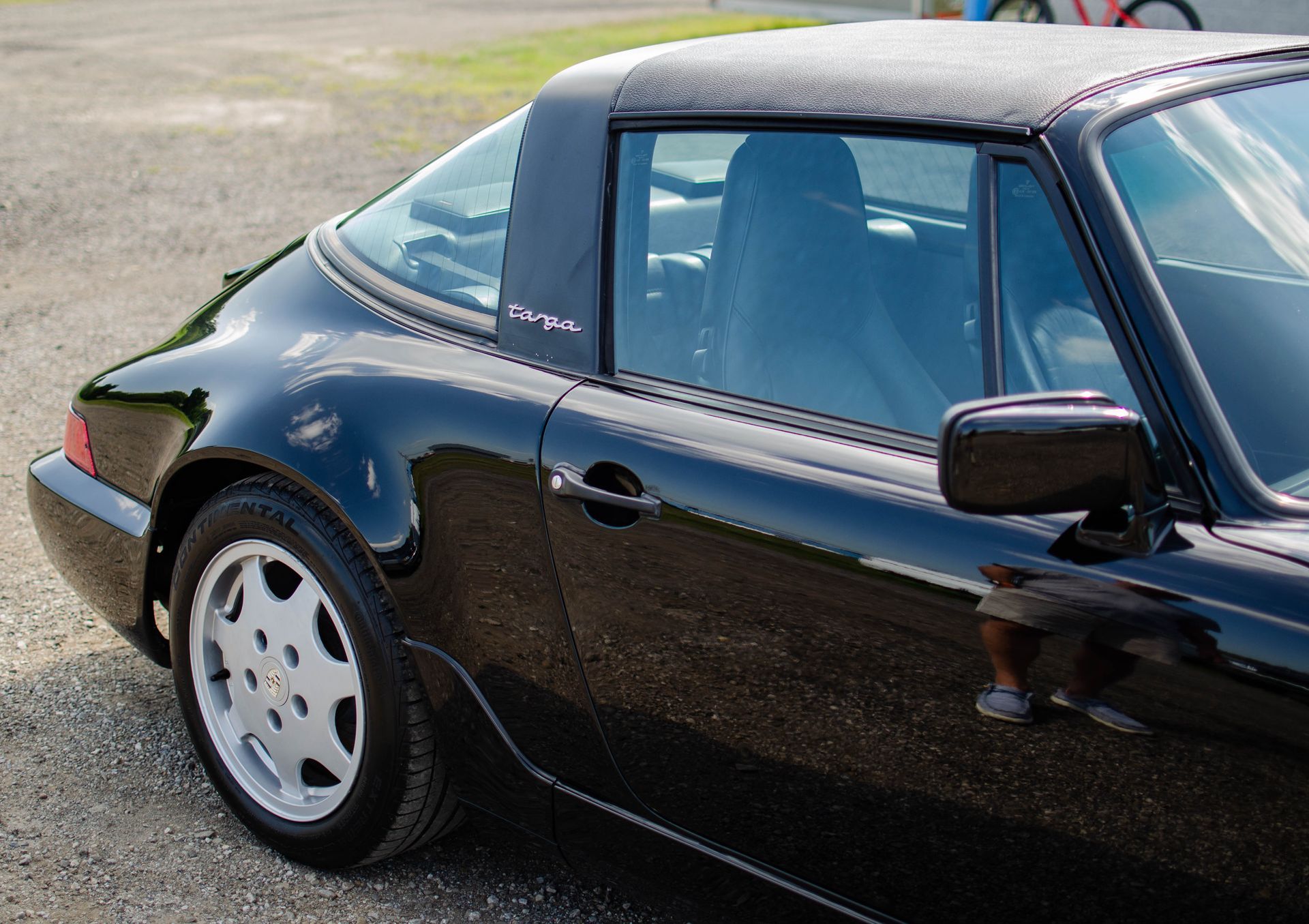 Black sports car parked outdoors, rear side view with silver roof and wheels
