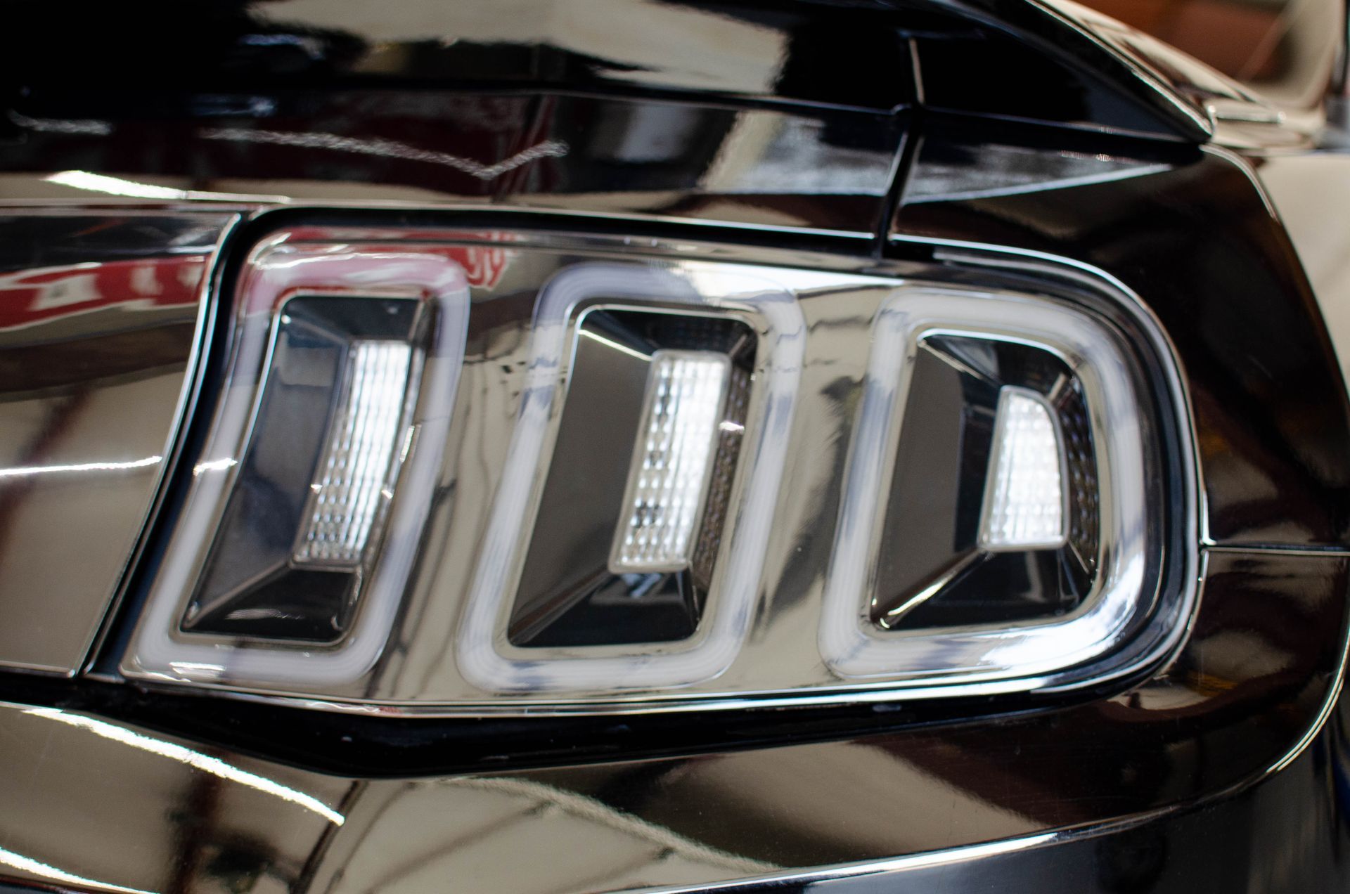 Close-up of a car’s chrome rear taillight with three illuminated-looking rectangular segments