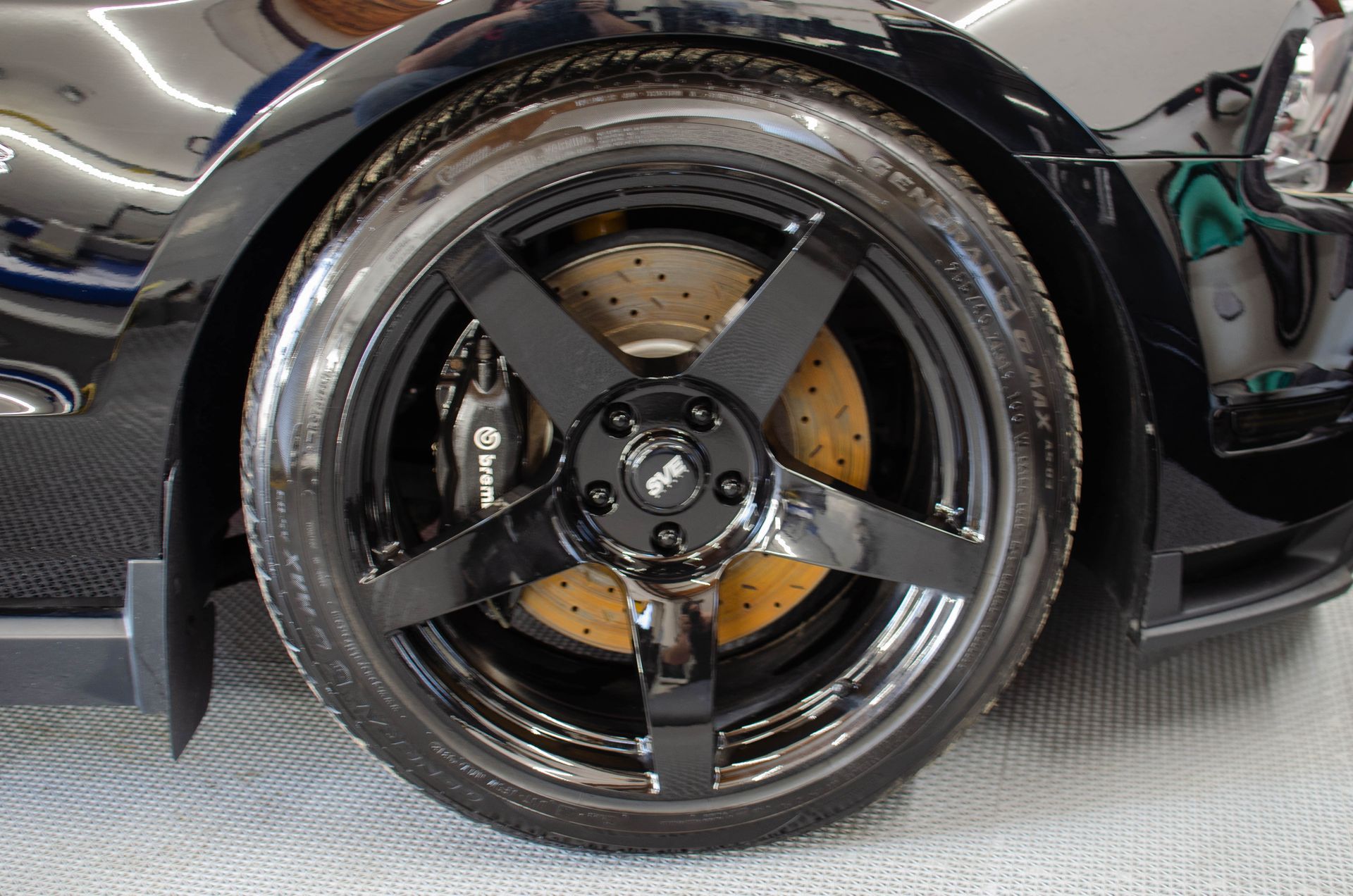 Close-up of a black sports car wheel with chrome rim and orange brake caliper