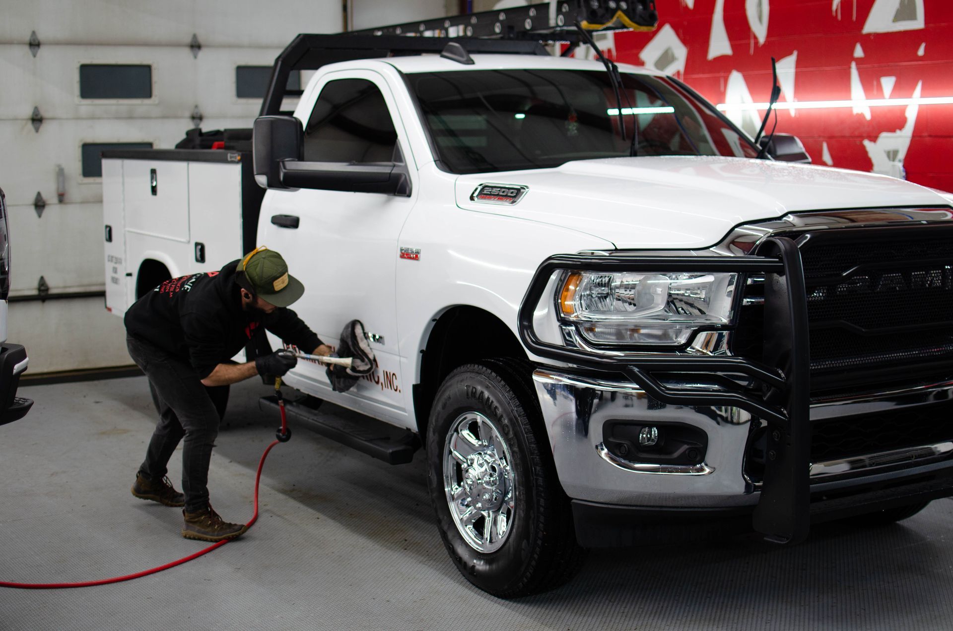 Person polishing a white pickup truck in a garage showroom