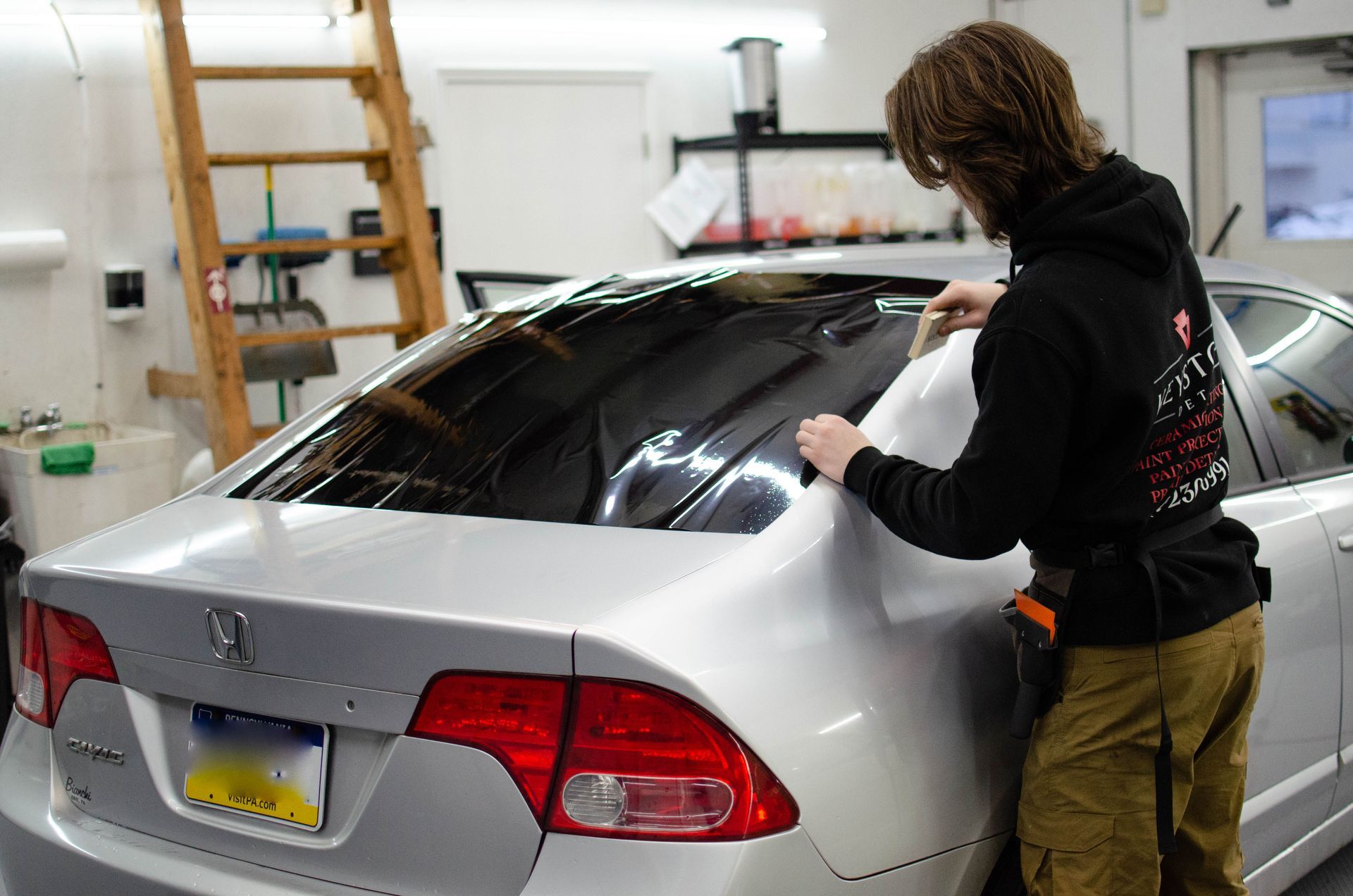 a man with a tattoo on his arm is cleaning the windshield of a car .