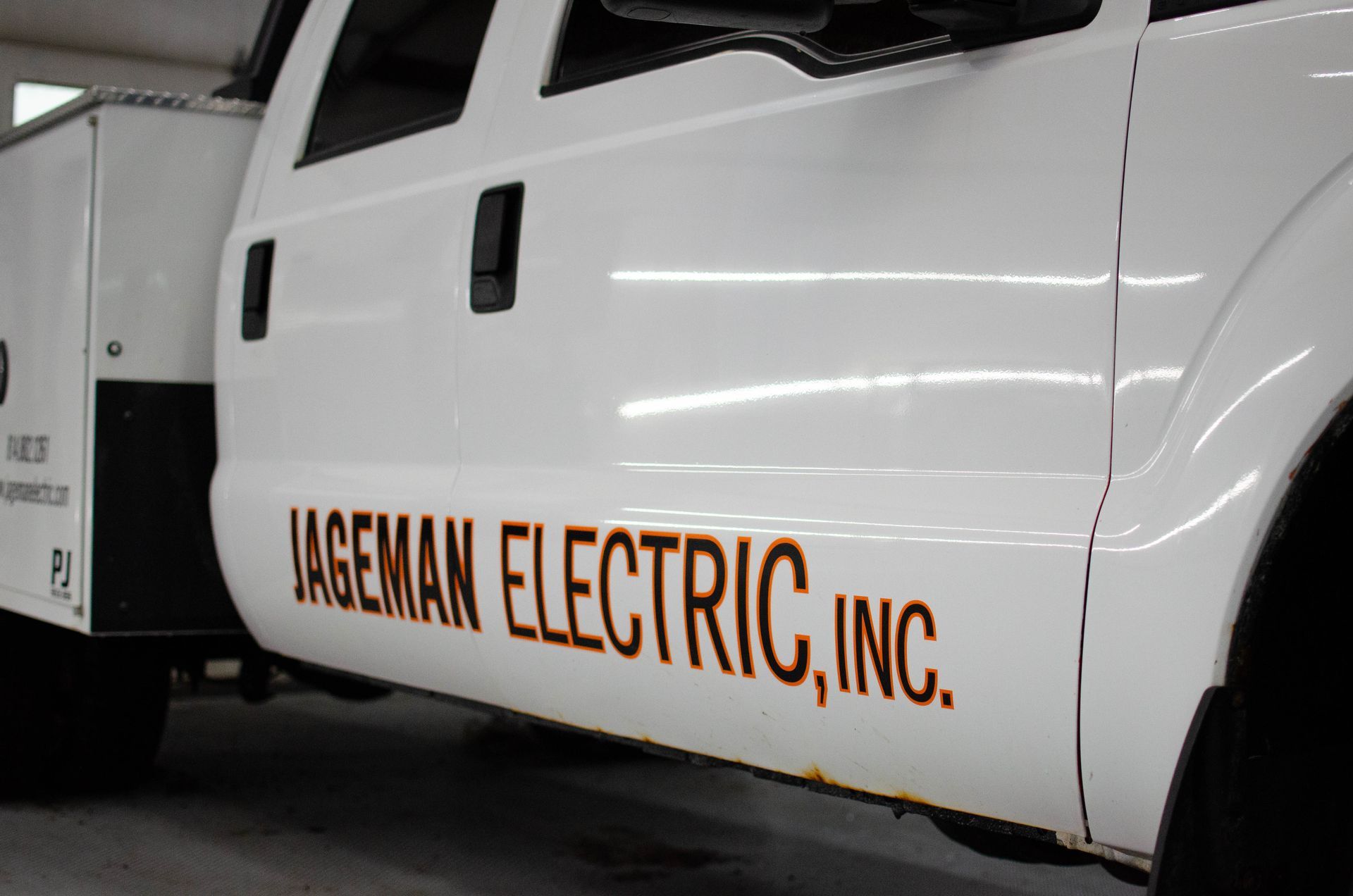 White utility truck with “LAGEMAN ELECTRIC, INC.” lettering on the side in a garage.