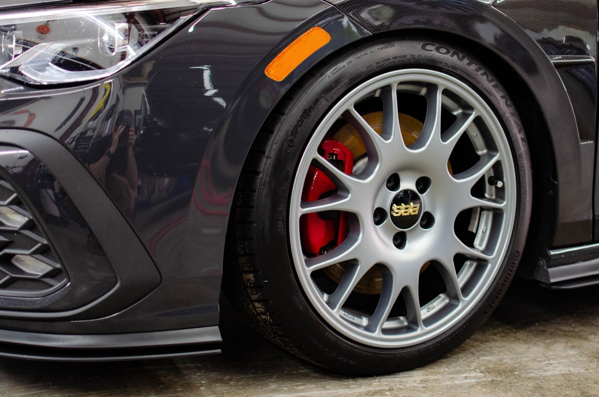 Close-up of a black sports car’s silver wheel with red brake caliper and low-profile tire
