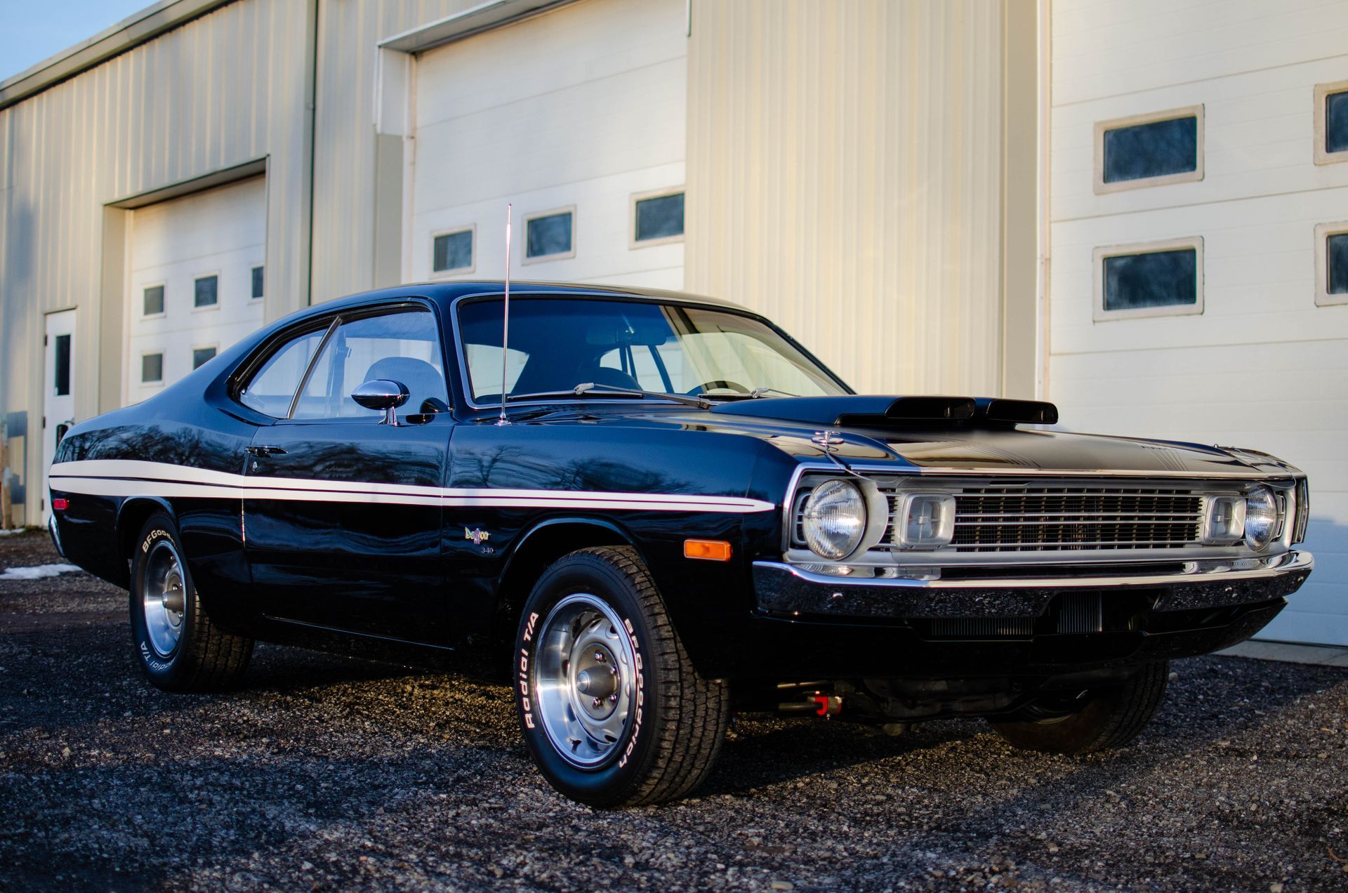 Black classic muscle car parked outside a garage with white doors
