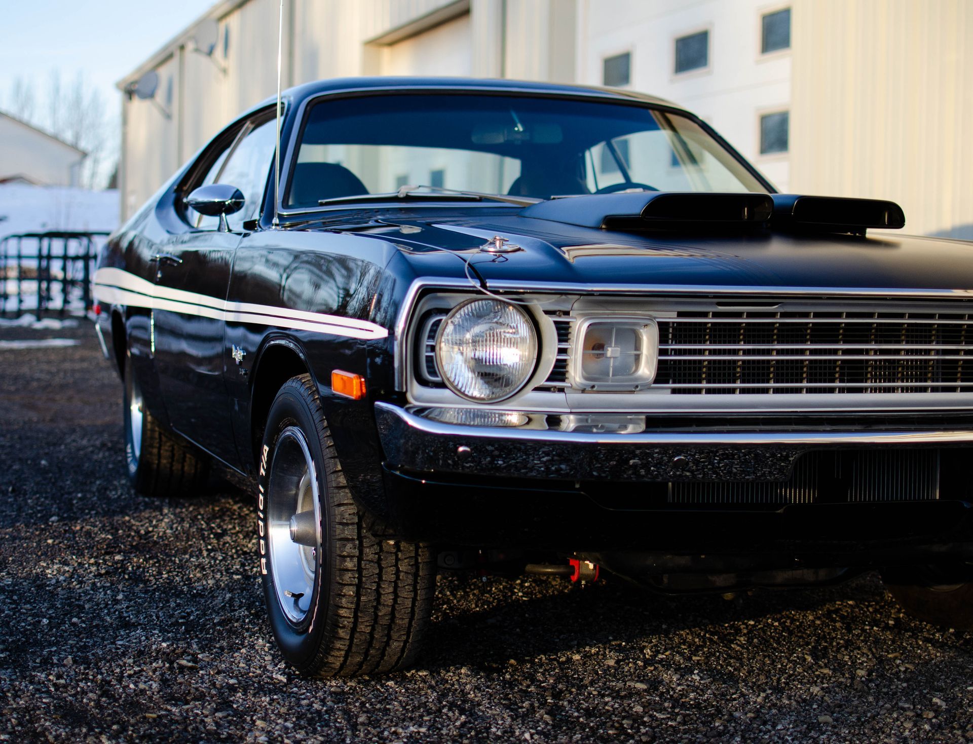 Classic black vintage car parked outdoors beside a building.