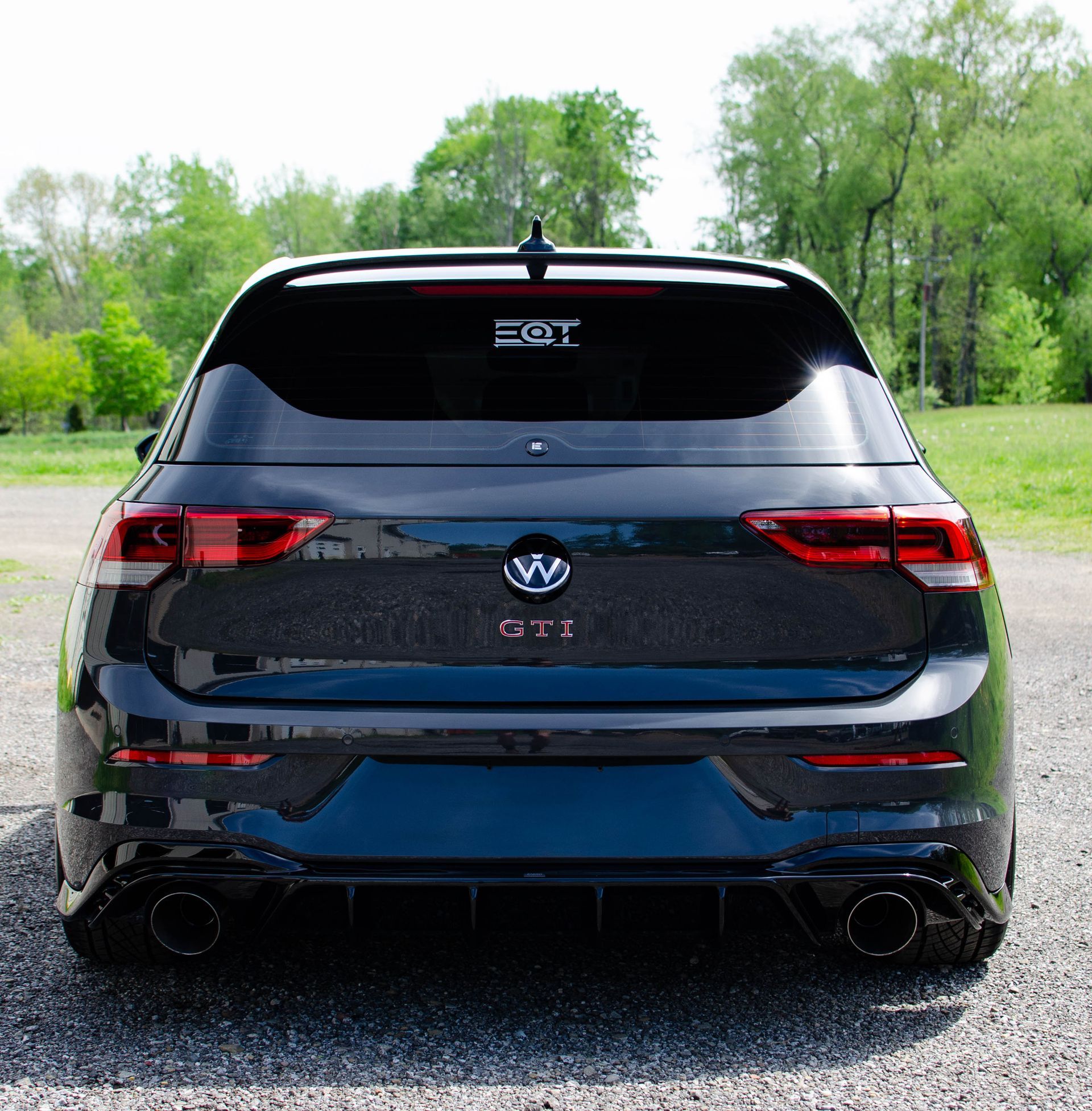 Black Volkswagen SUV seen from the rear on a gravel road with trees in the background