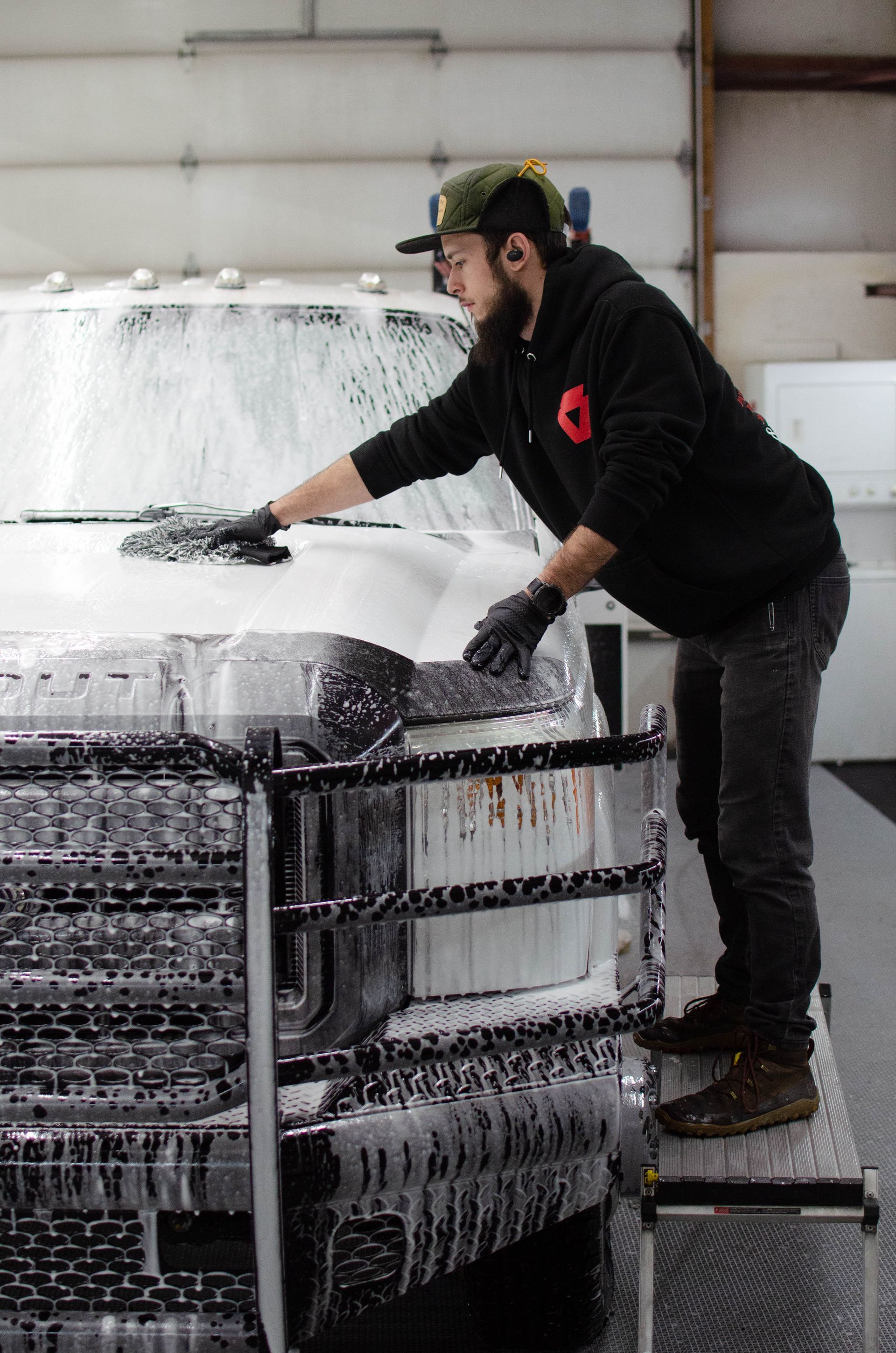 Worker spraying foam onto stacked metal coils in an industrial workshop