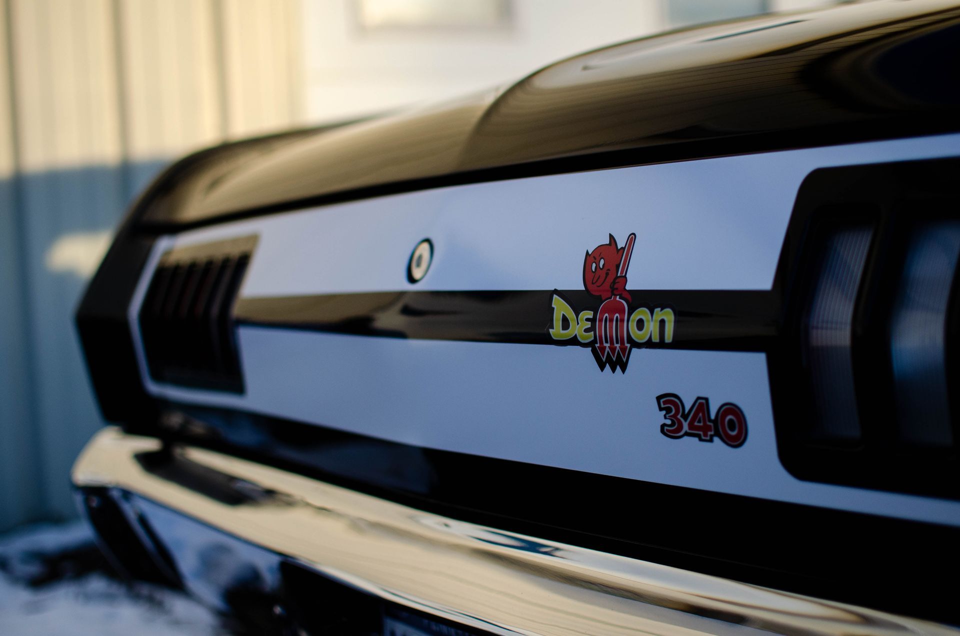 Close-up of a black car trunk with a “Demon 340” badge and chrome trim.