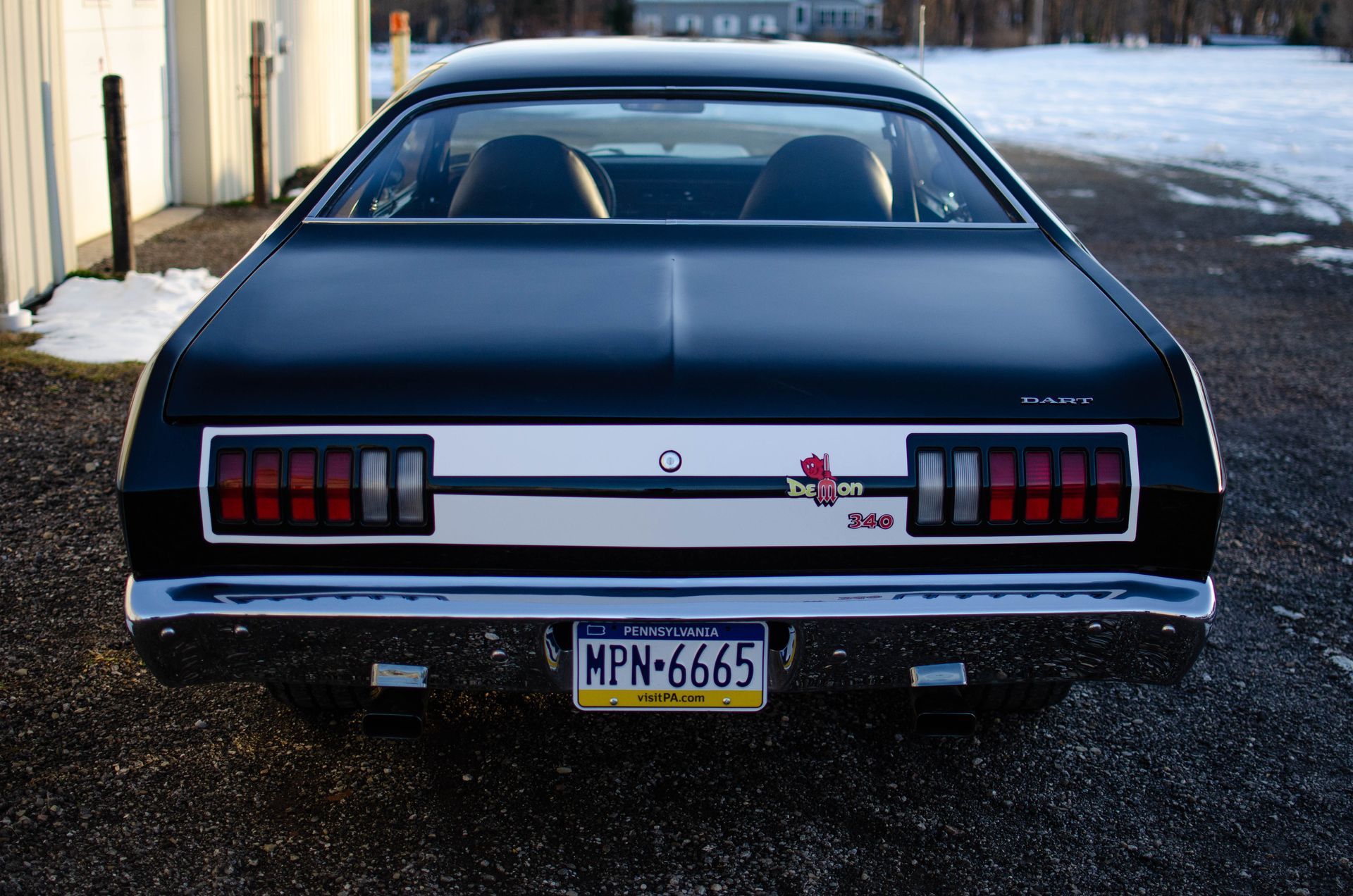 Rear view of a dark blue classic car parked on a snowy street
