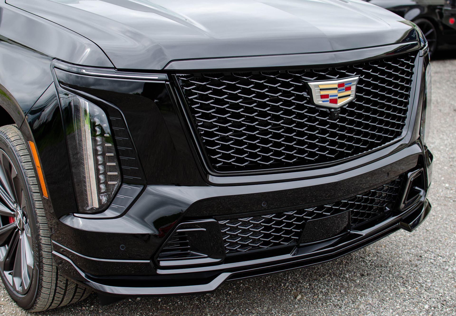 Front view of a black Cadillac SUV with a chrome grille and emblem, parked outdoors.