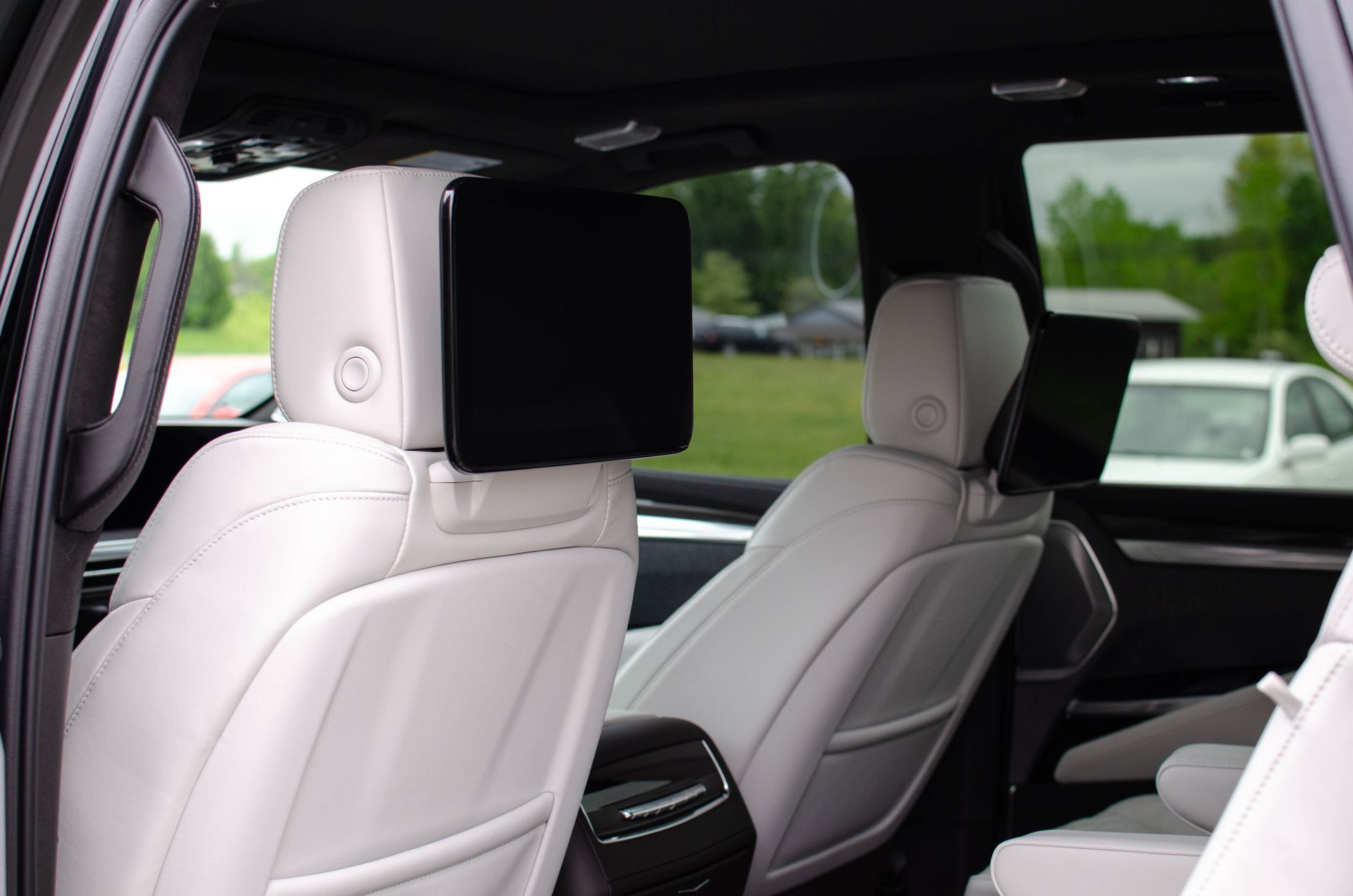 White leather car seats with headrest screens inside a luxury vehicle