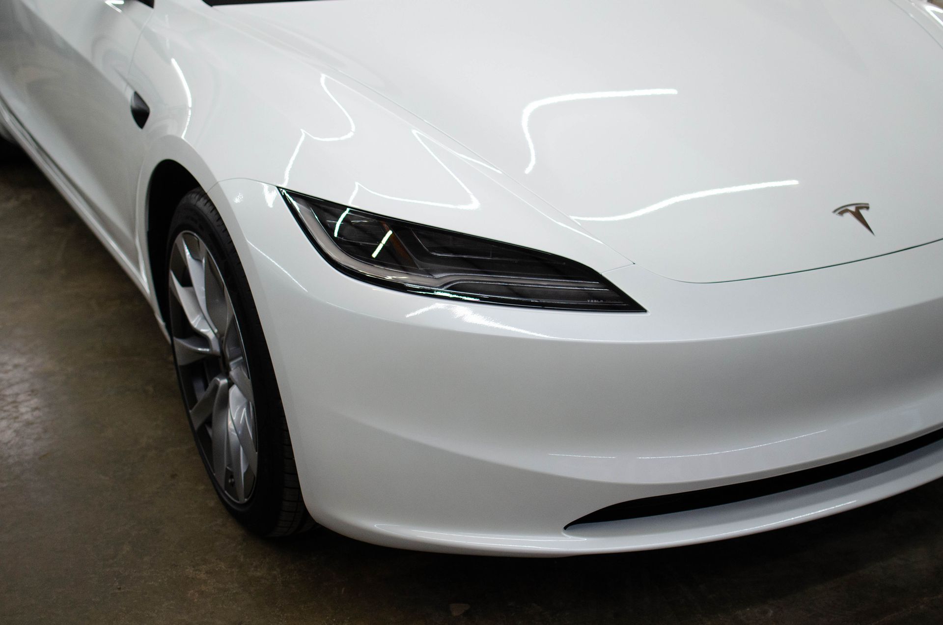 Front view of a white Tesla sedan in a garage