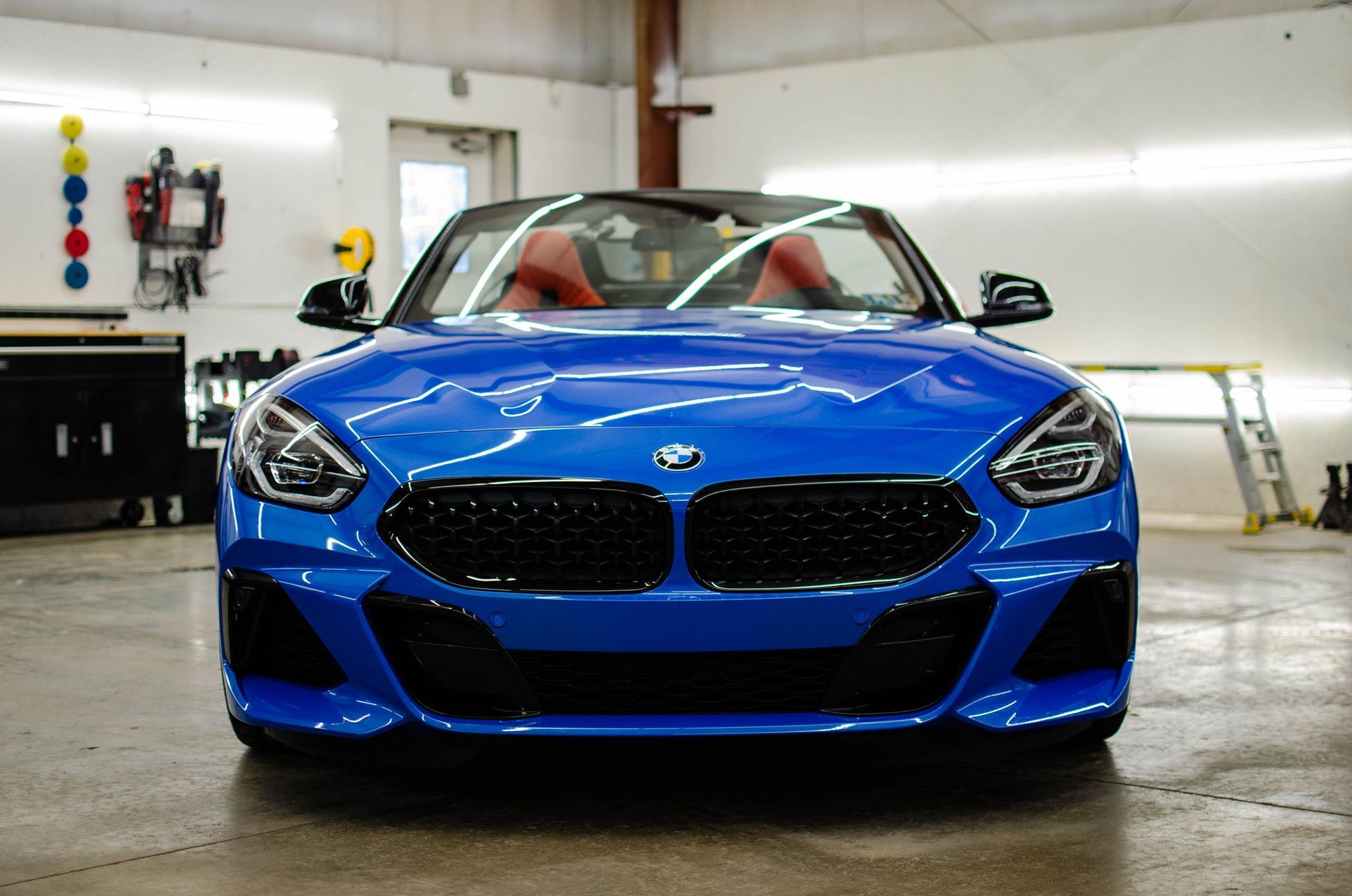 Blue sports car parked in a garage, front view with headlights and grille visible