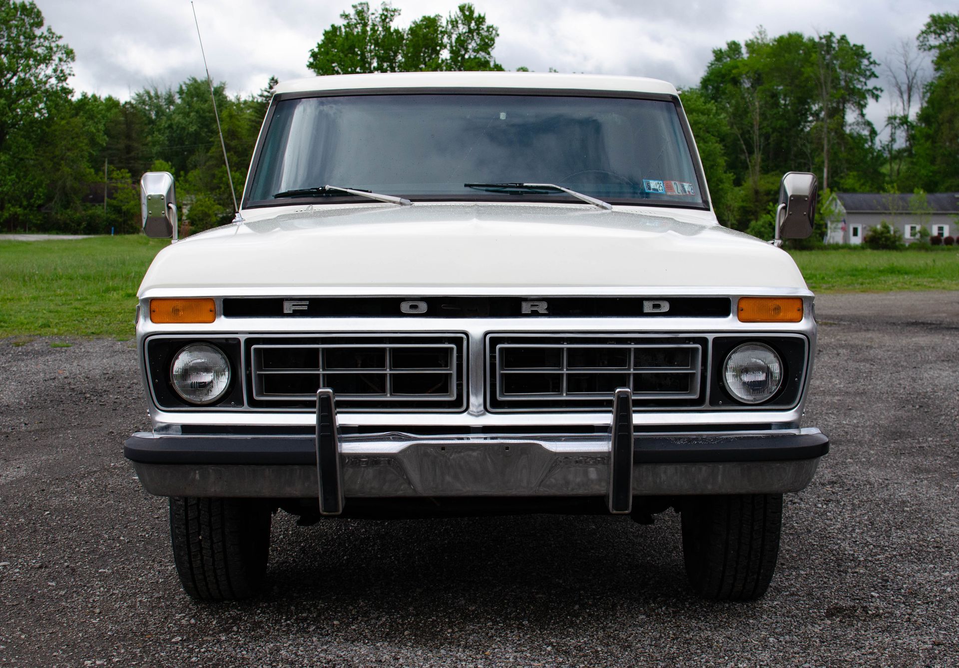 Front view of a white vintage Ford pickup truck parked on a gravel lot
