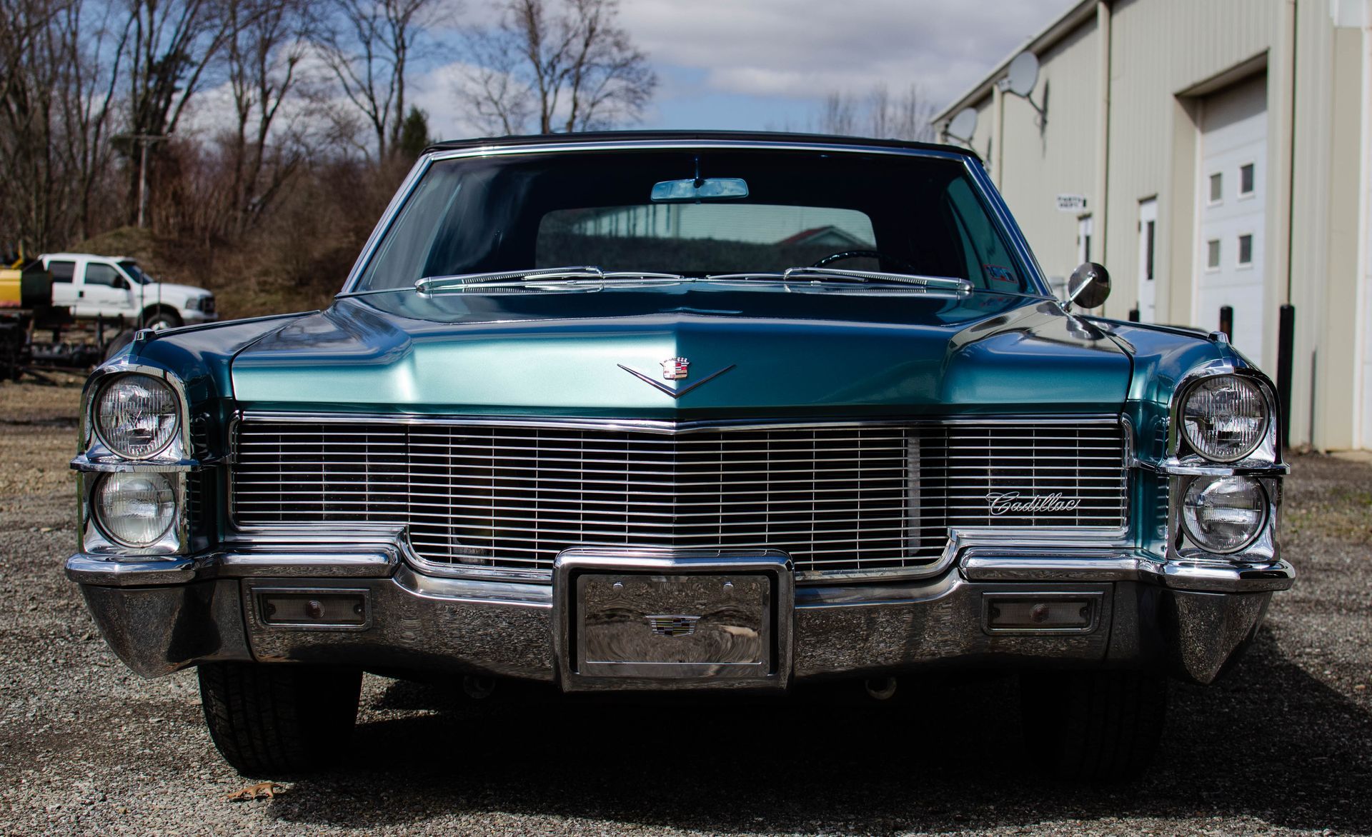 Front view of a turquoise classic Cadillac parked outside a building