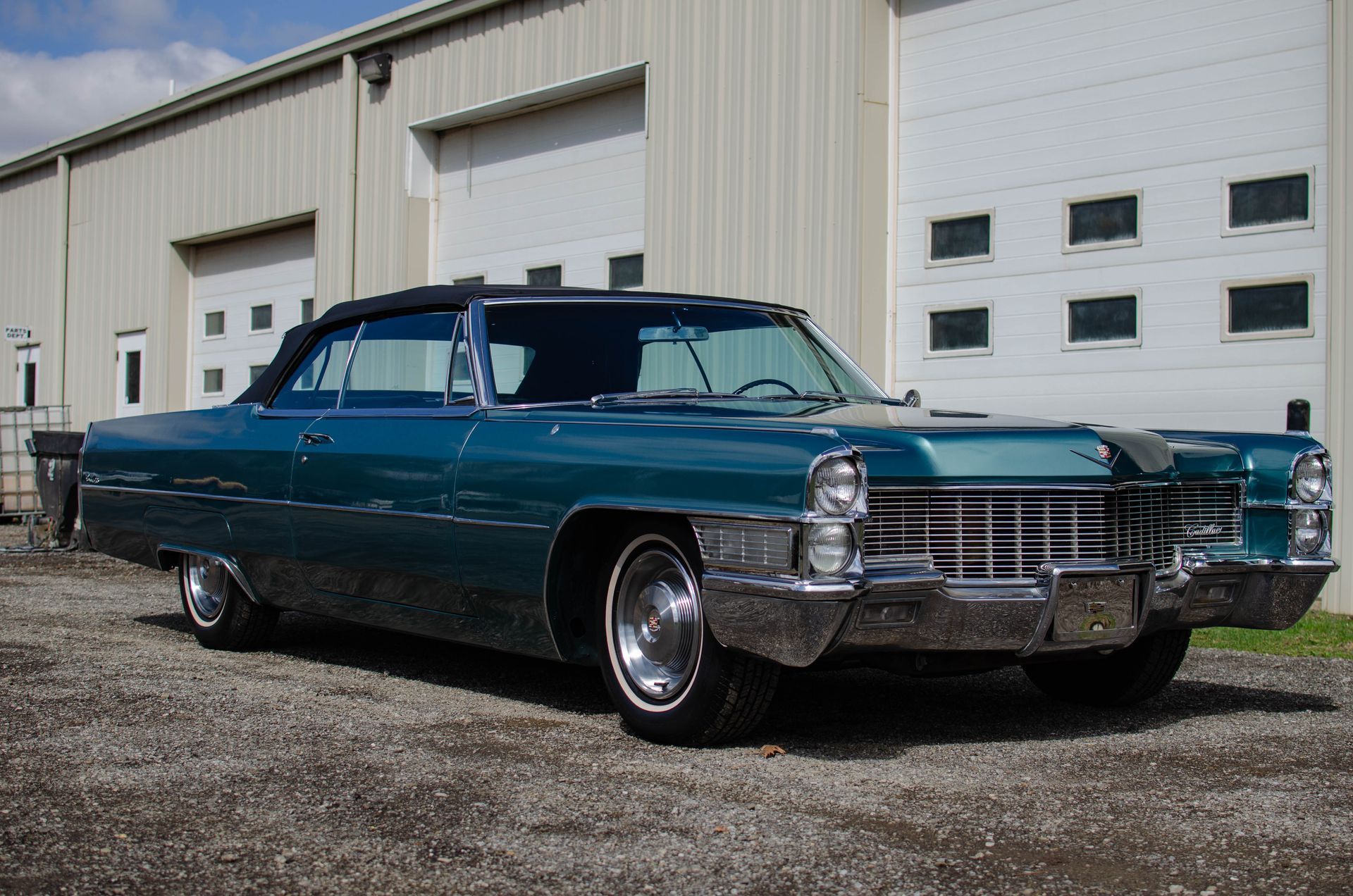 Teal classic Cadillac parked outside a beige warehouse