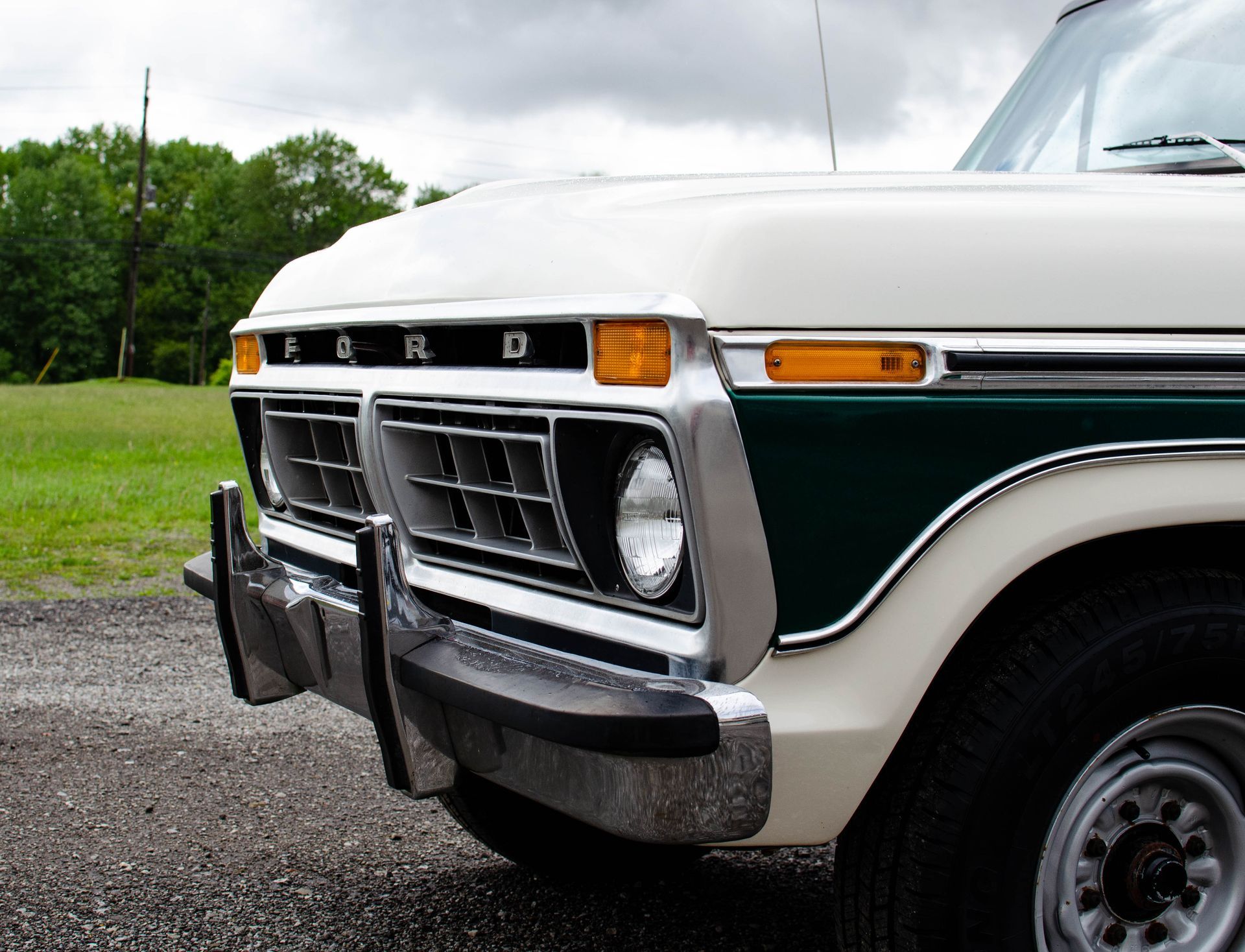 Vintage white and green Ford truck front end parked on a gravel roadside