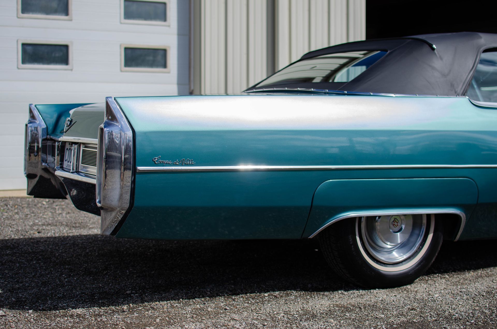 Turquoise vintage car parked in front of a garage door