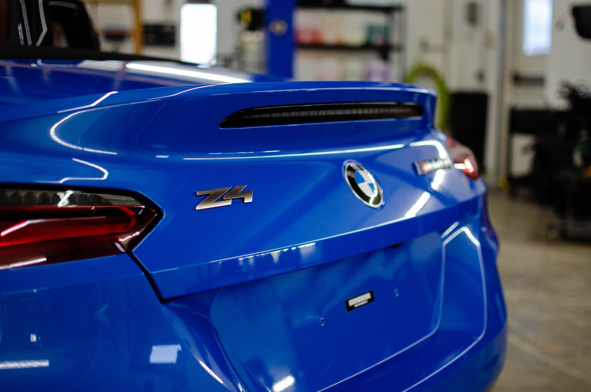 Blue BMW Z4 rear view in a garage, with taillights and trunk badge visible