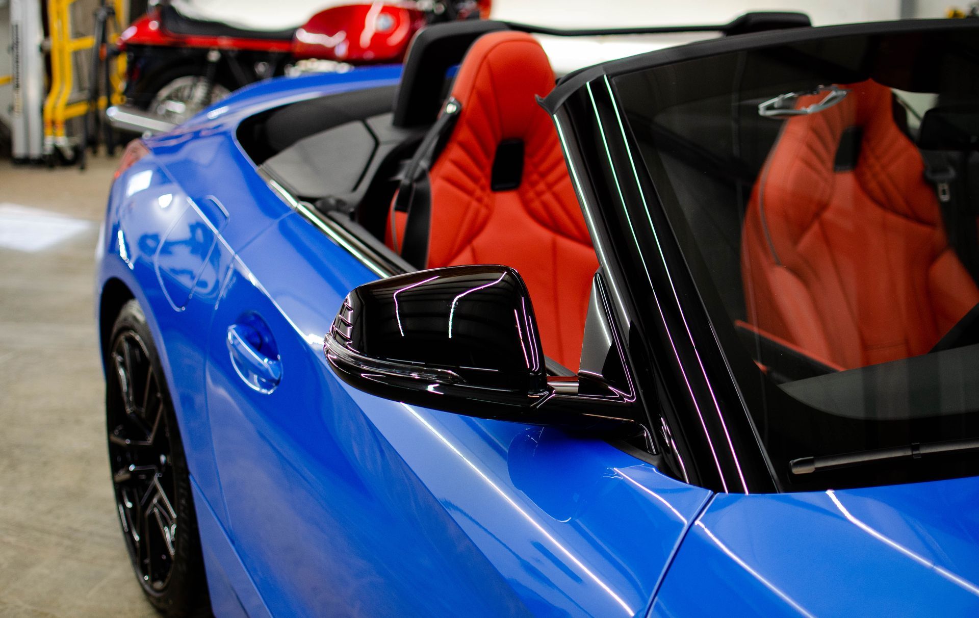Blue convertible sports car with red interior on display indoors