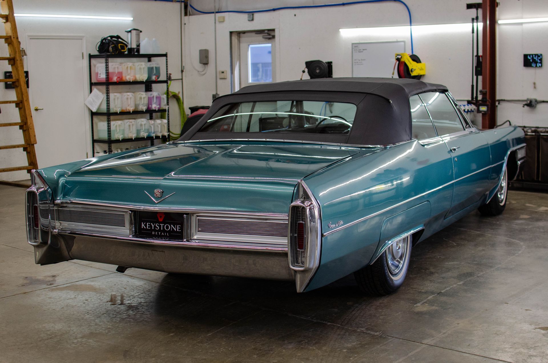 Teal classic Cadillac parked in a garage, rear view with tail fins and chrome trim