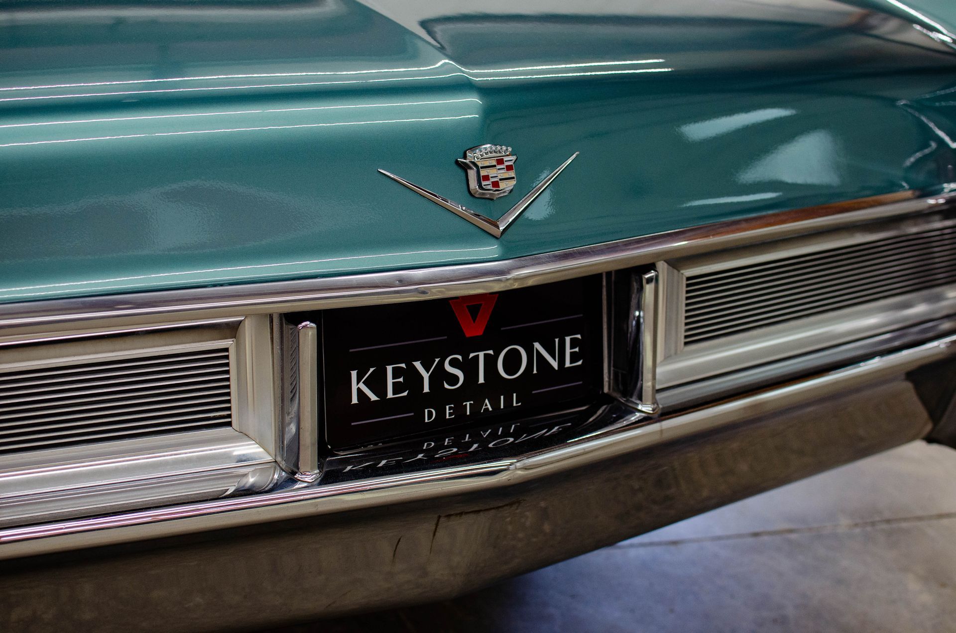 Close-up of a teal classic car grille with a Keystone Detail license plate
