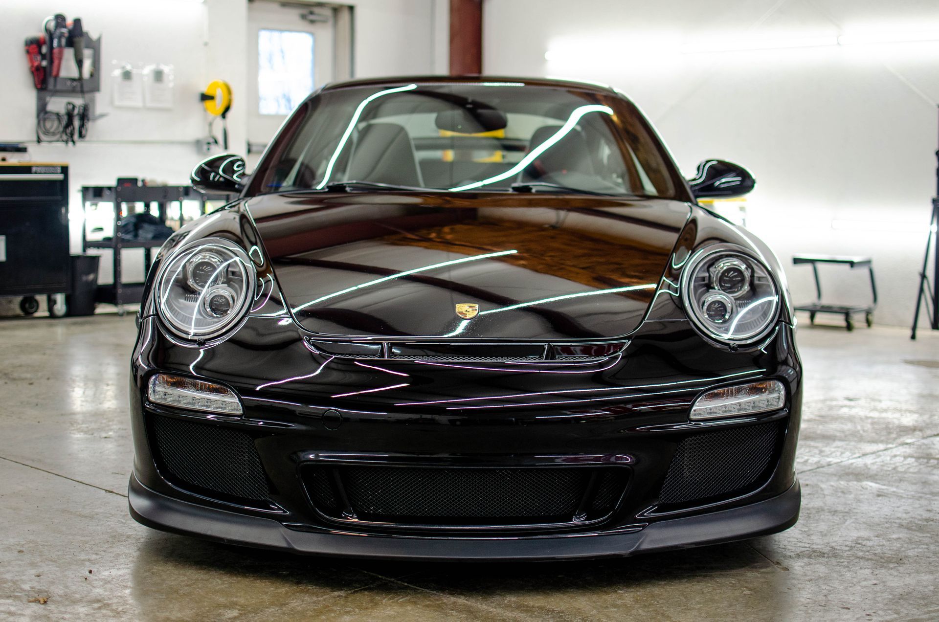 Front view of a dark brown Porsche 911 parked in a garage