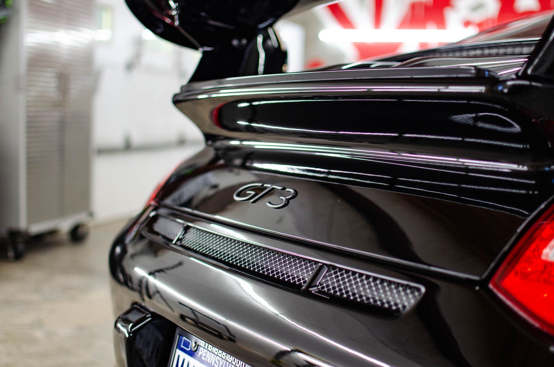 Rear view of a black Porsche 911 GT3 in a garage, showing the spoiler and taillight detail