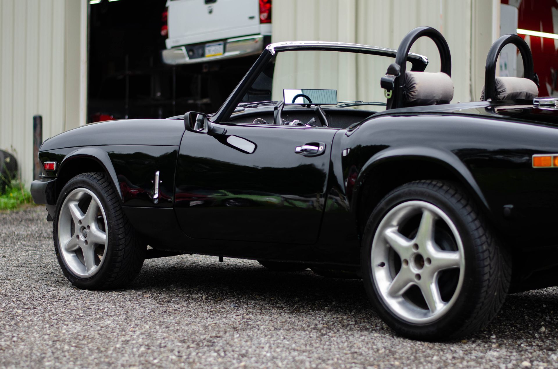 Black sports car parked on gravel beside a building