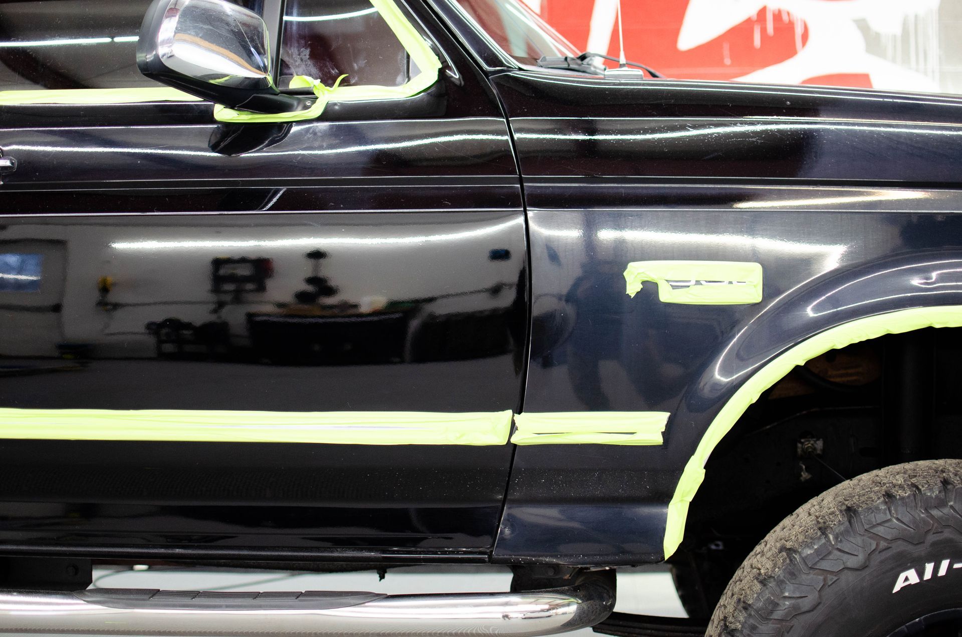 Black pickup truck with neon yellow trim and chrome step bar, shown from the side.