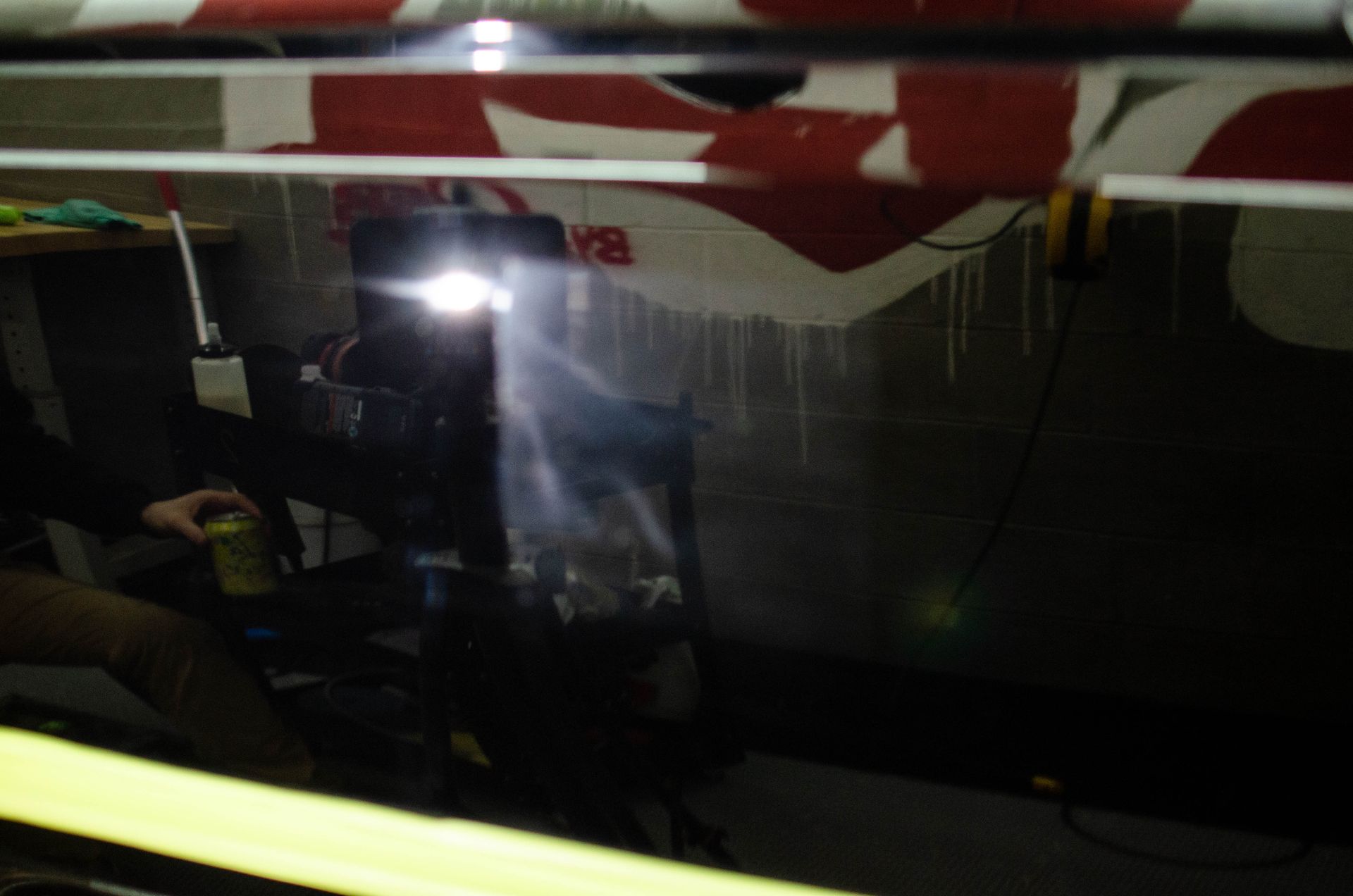 Dim interior with a bright light reflection on a dark window and red-and-white markings overhead