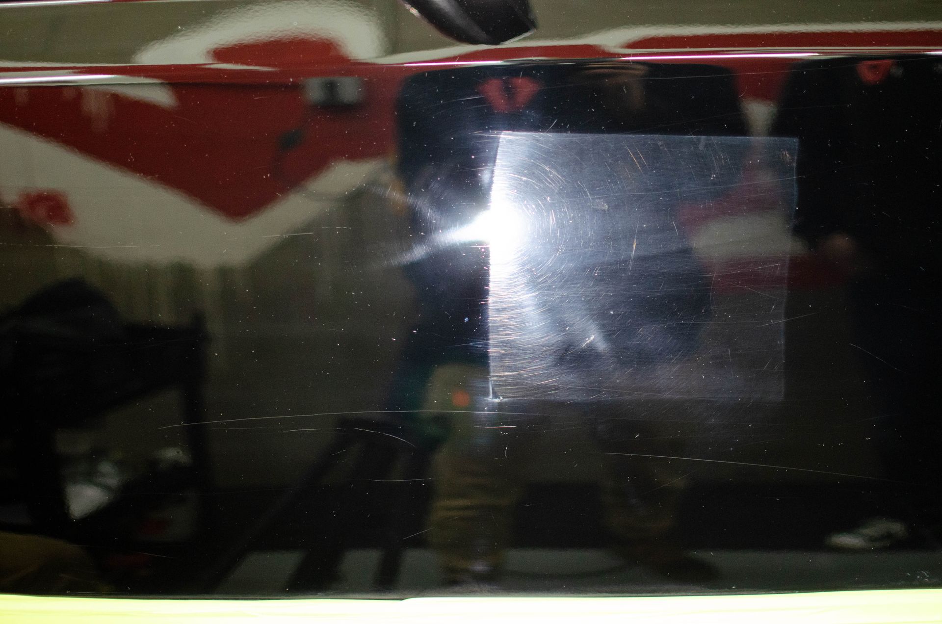 Dark reflective glass window with a bright glare and blurry indoor reflections