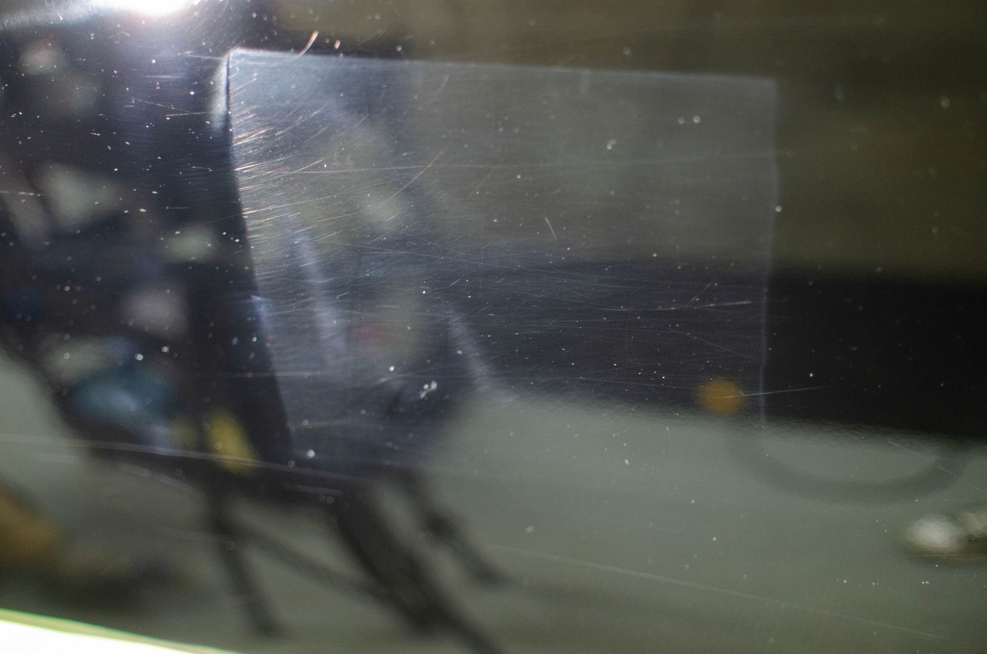 Blurred close-up of a reflective glass surface with faint lights and a dark background