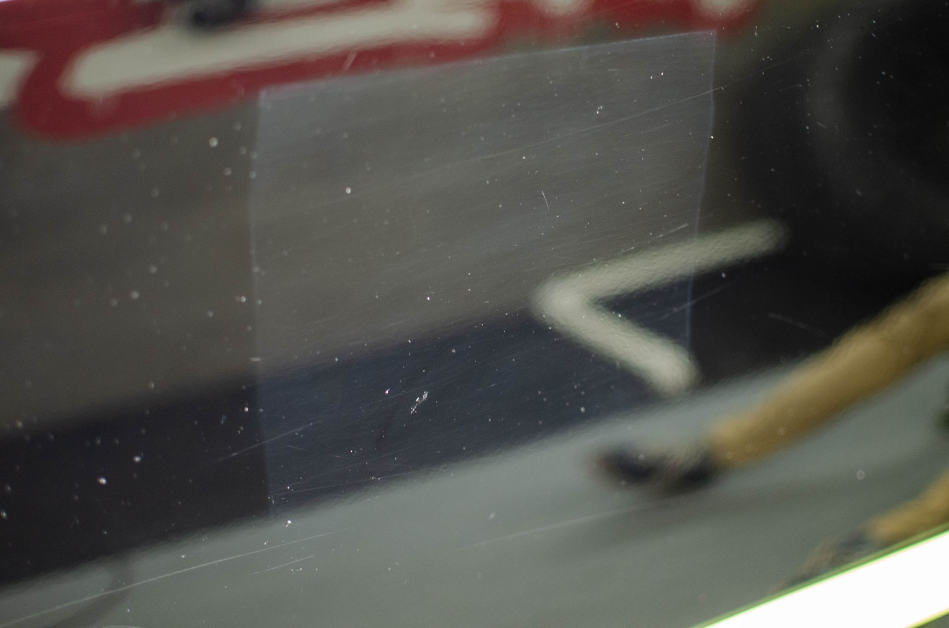 Blurred close-up of a person’s leg and shoe near a white floor marking on a red-and-black surface