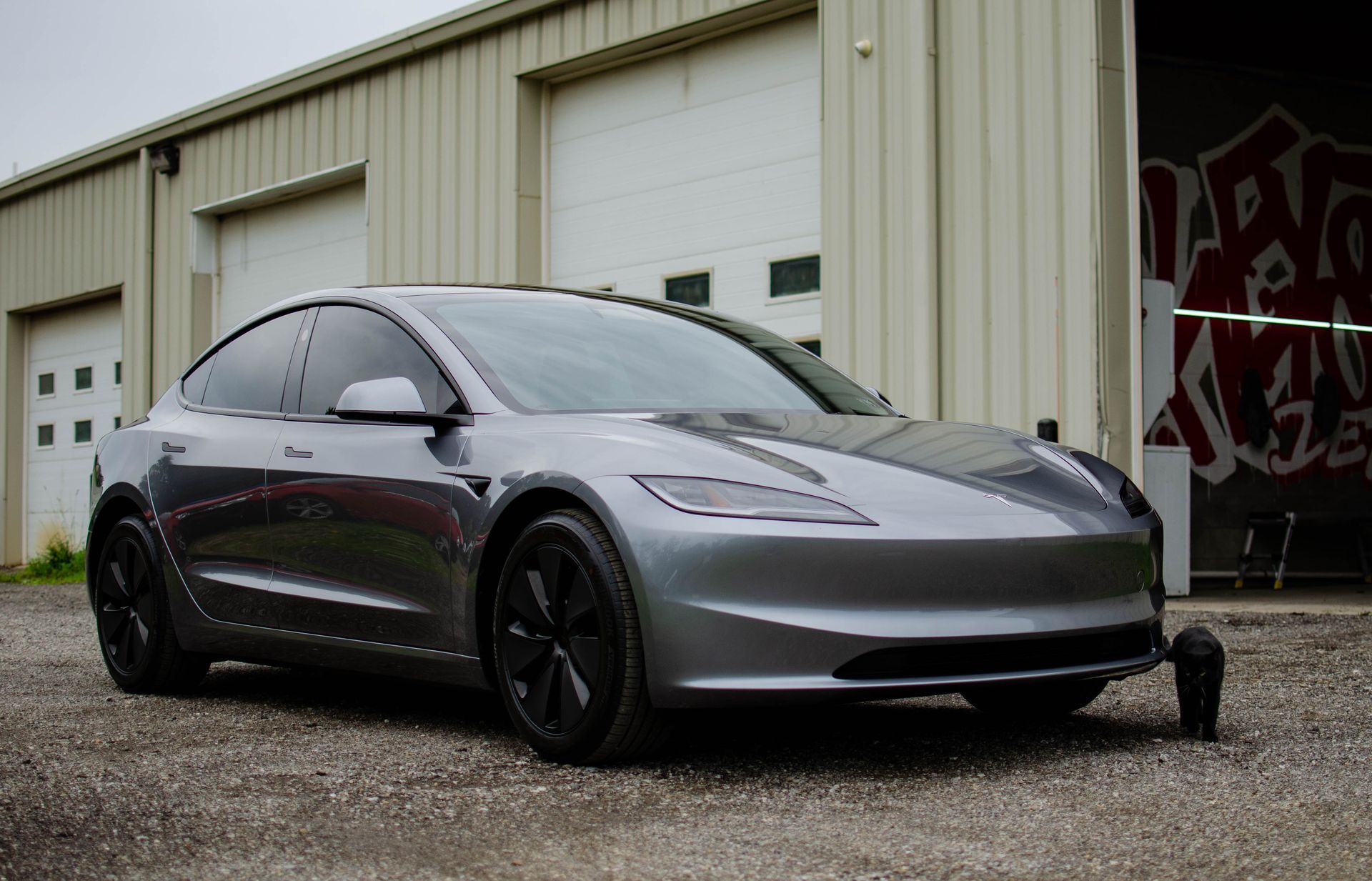 Gray Tesla sedan parked outside a warehouse