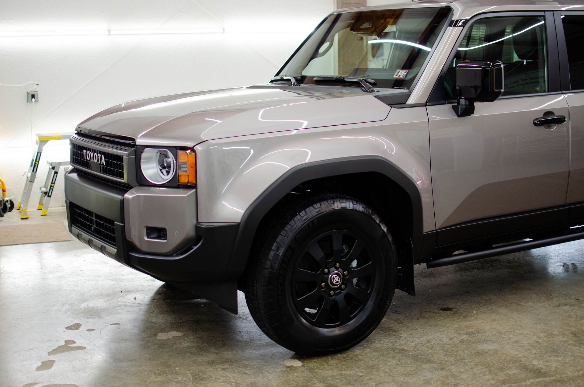 Beige SUV with black wheels parked indoors in a garage.