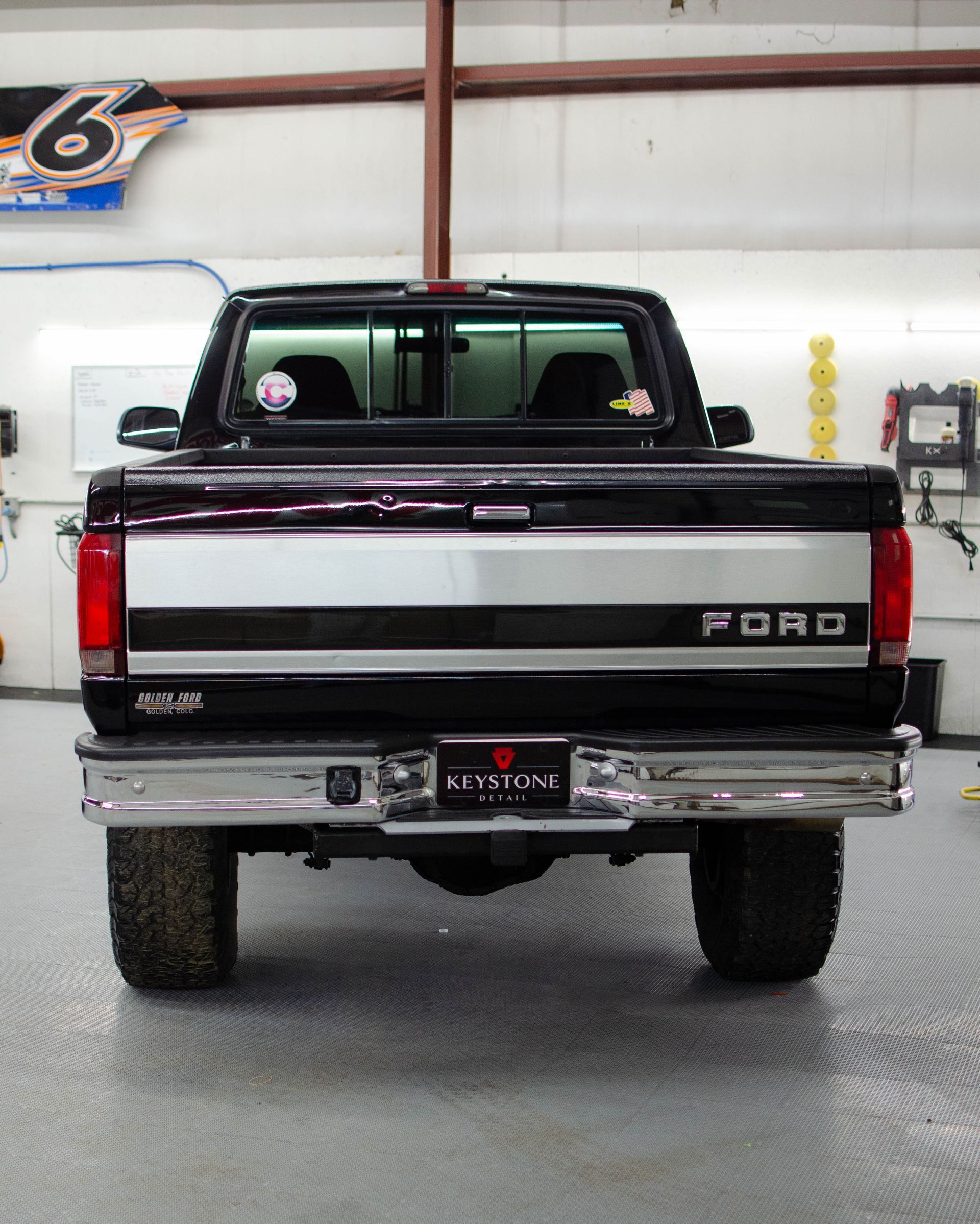 Rear view of a black Ford pickup truck parked indoors in a garage or showroom.