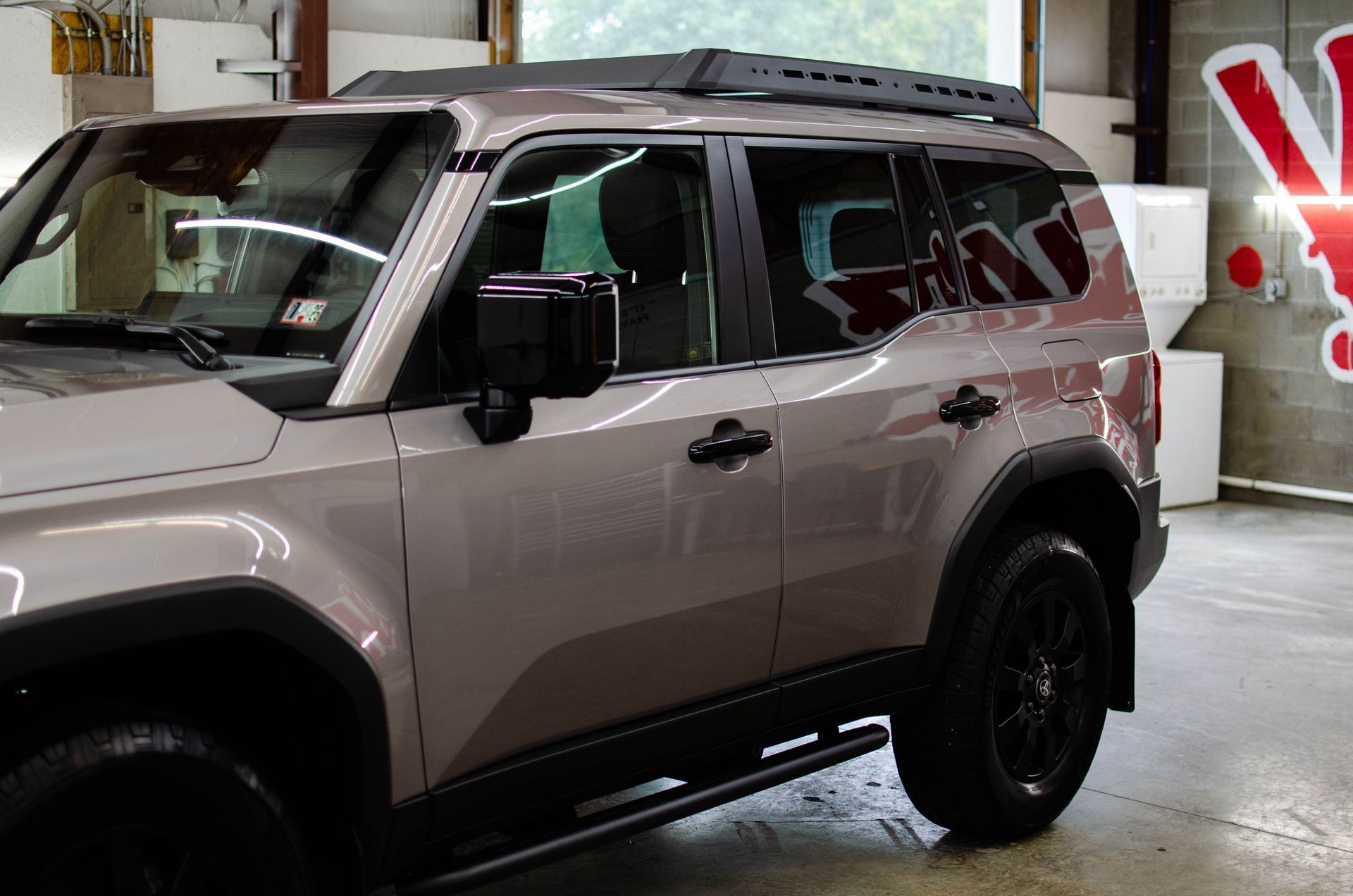 Light gray SUV parked indoors in a garage, shown from the front side.