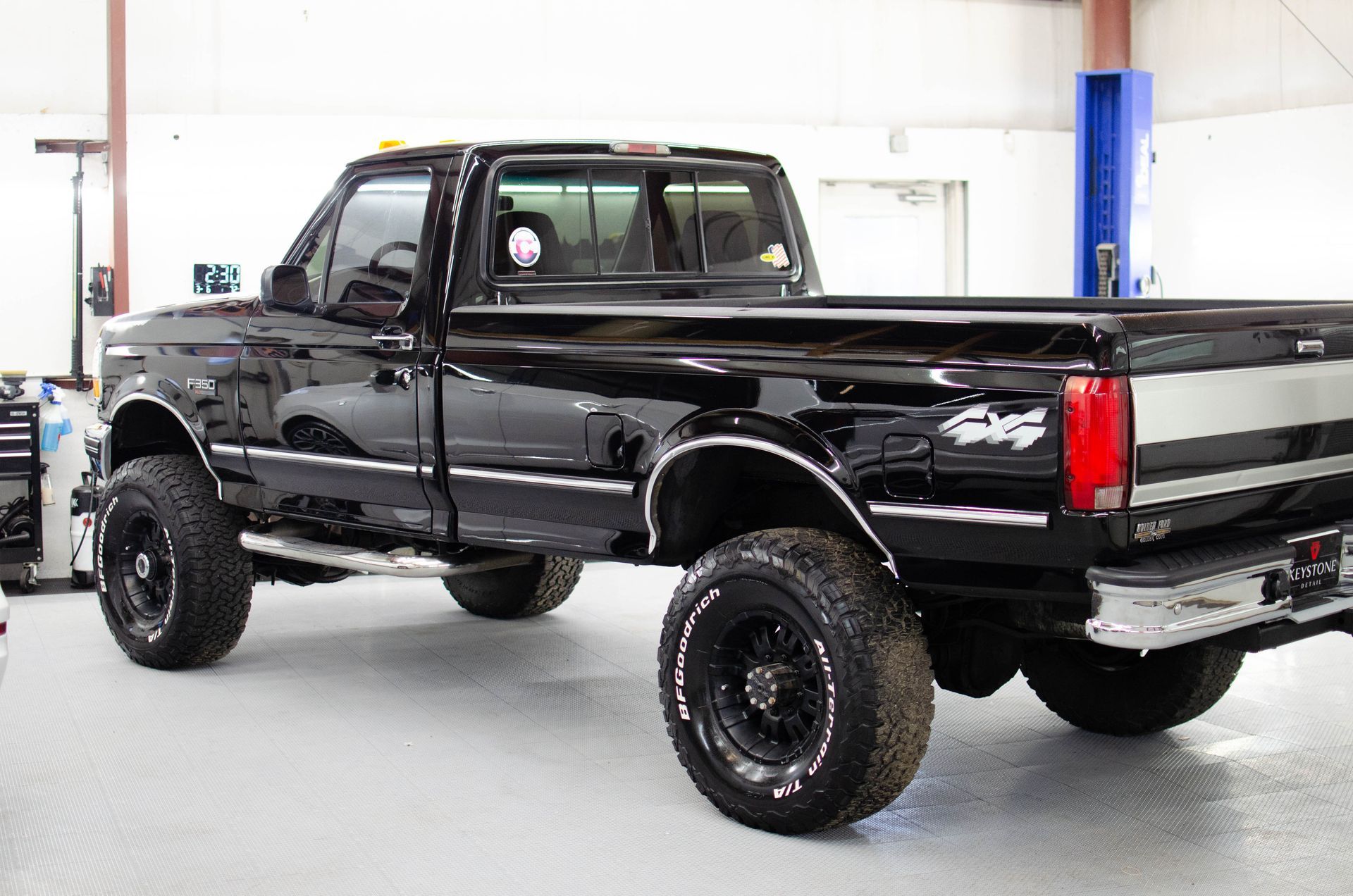 Black lifted pickup truck in a garage, viewed from the rear side.