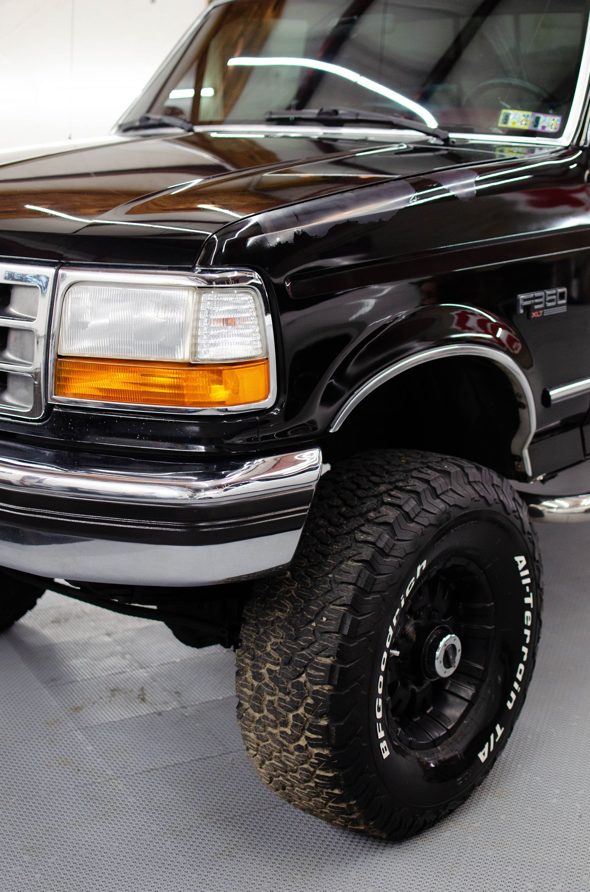 Black pickup truck with large off-road tires in a showroom or garage