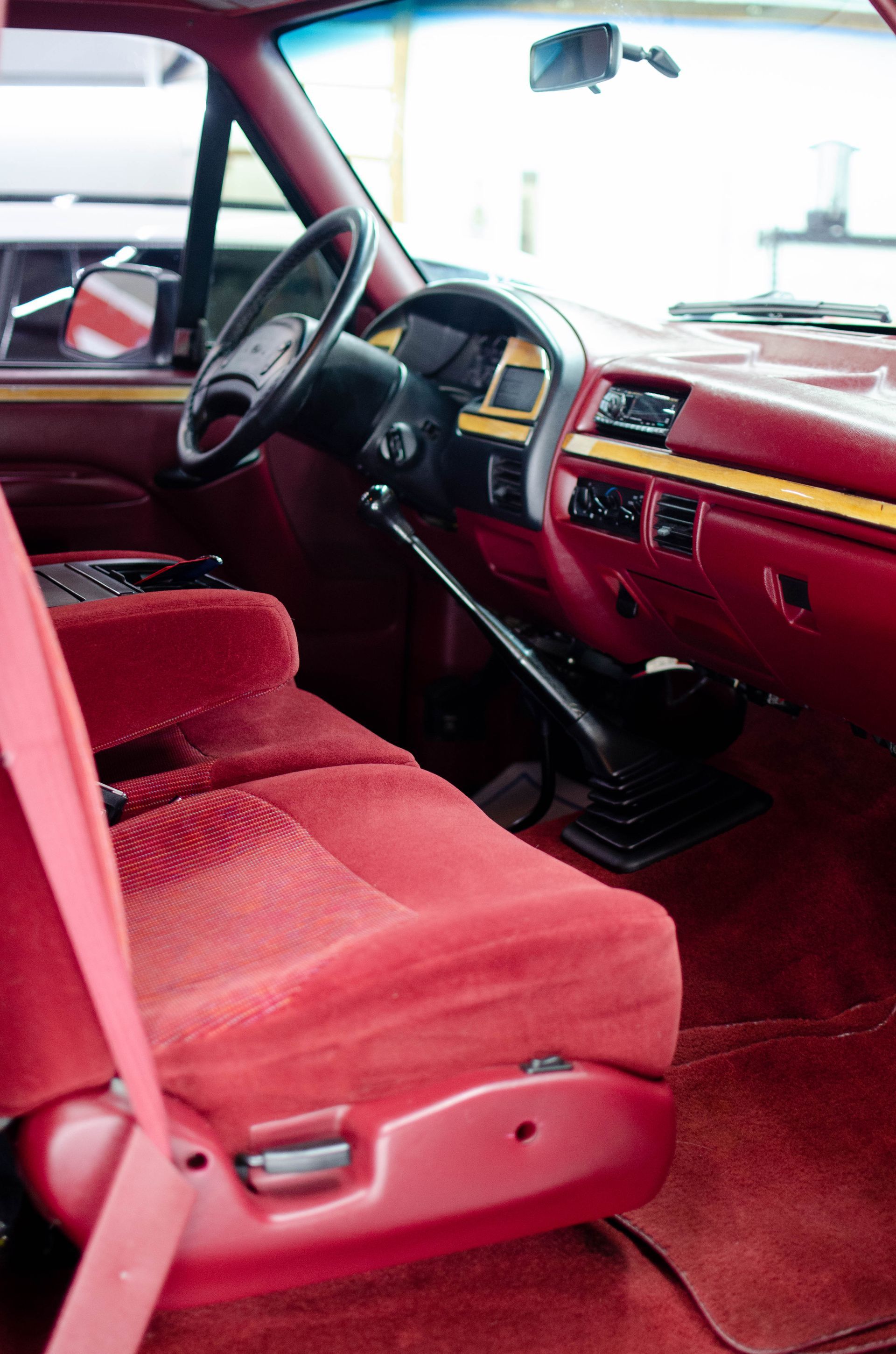 Red car interior with red upholstery, black steering wheel, and dashboard view from the driver’s side