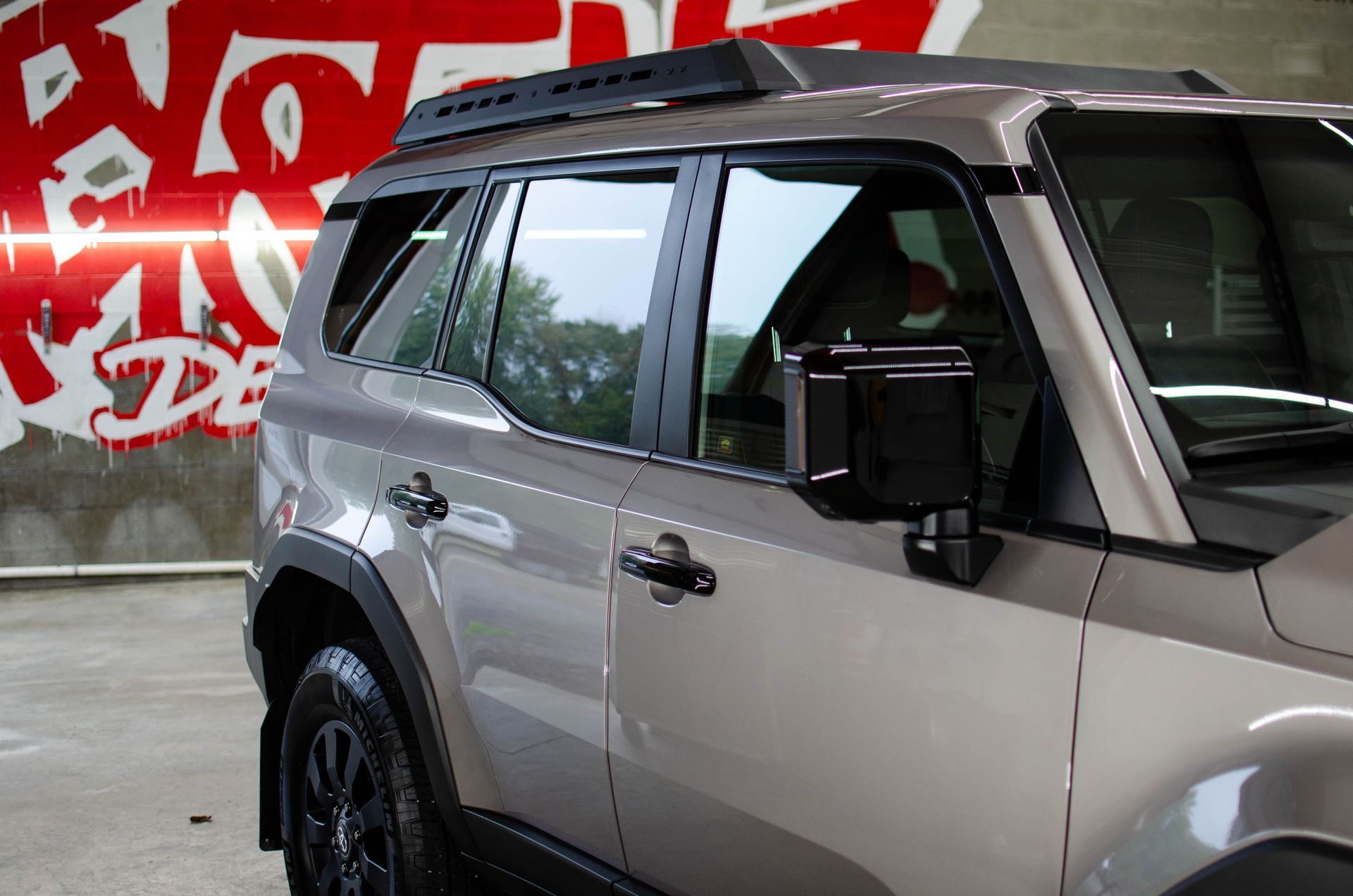 Silver SUV parked indoors against a red graffiti wall