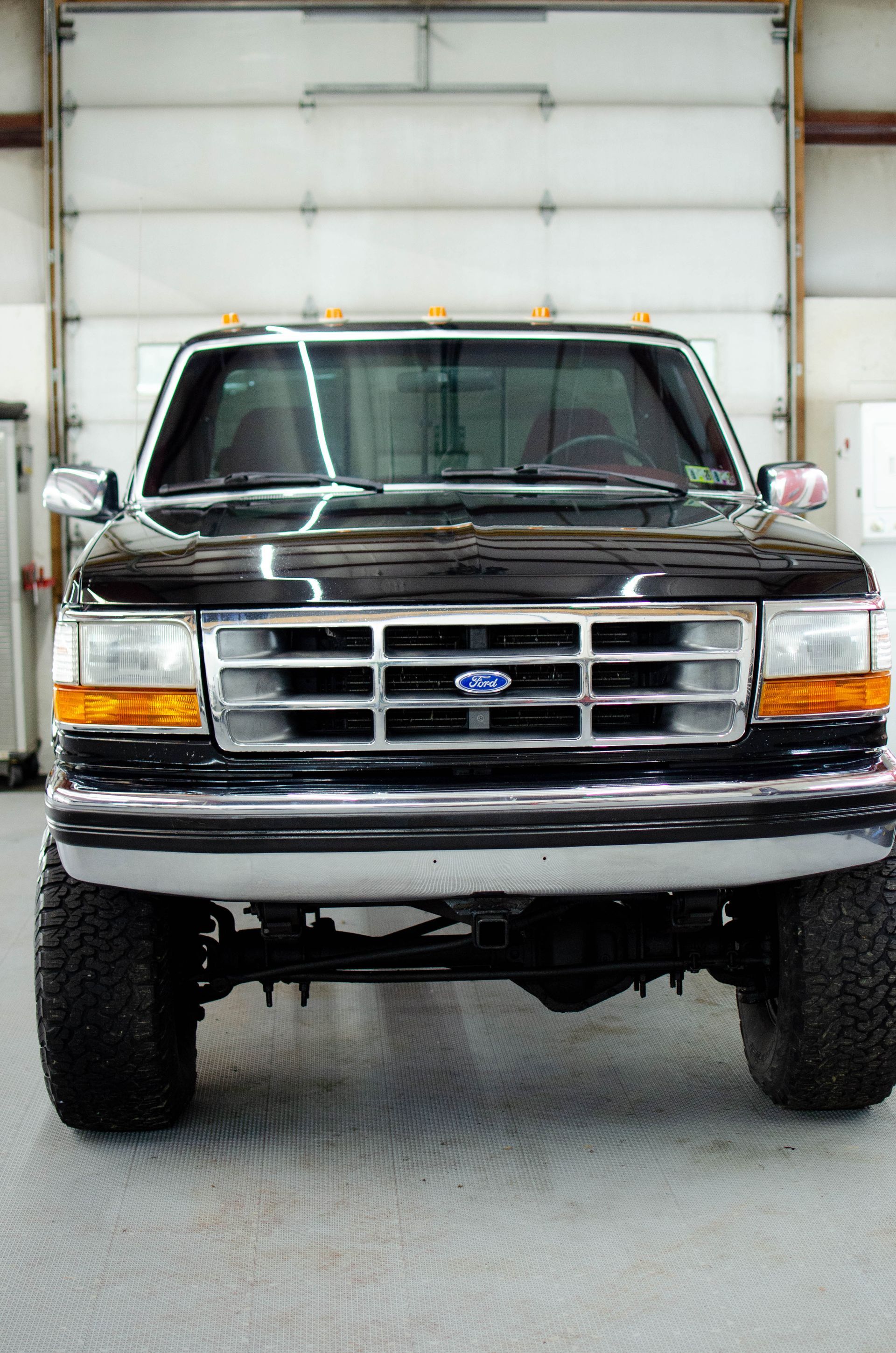 Front view of a black Ford pickup truck indoors against a white garage door