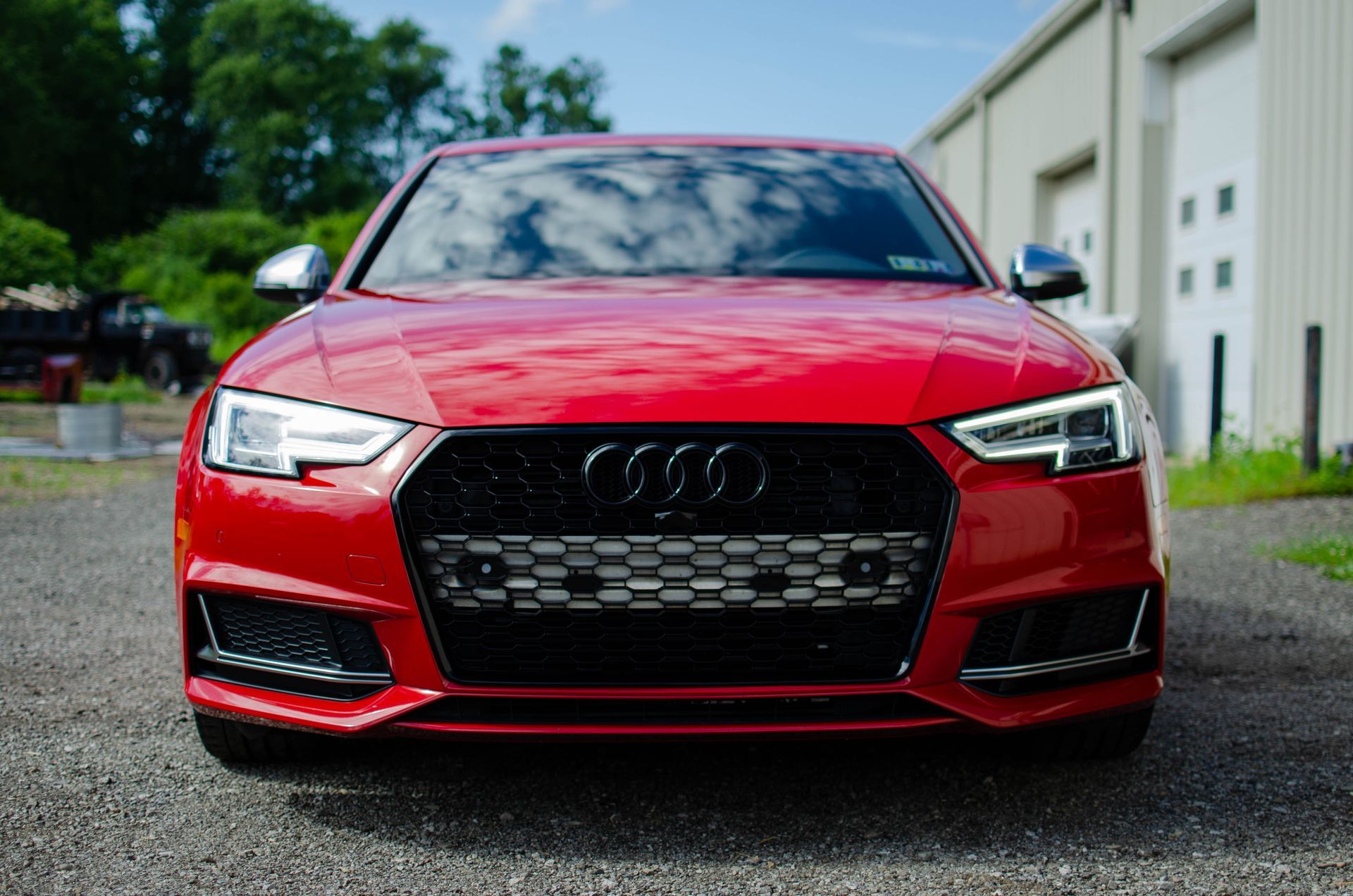 Red Audi sports car parked on a wet road outside a building