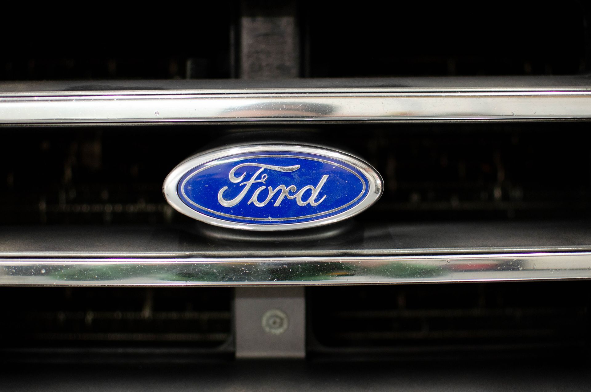 Blue Ford emblem on a car grille with chrome horizontal bars