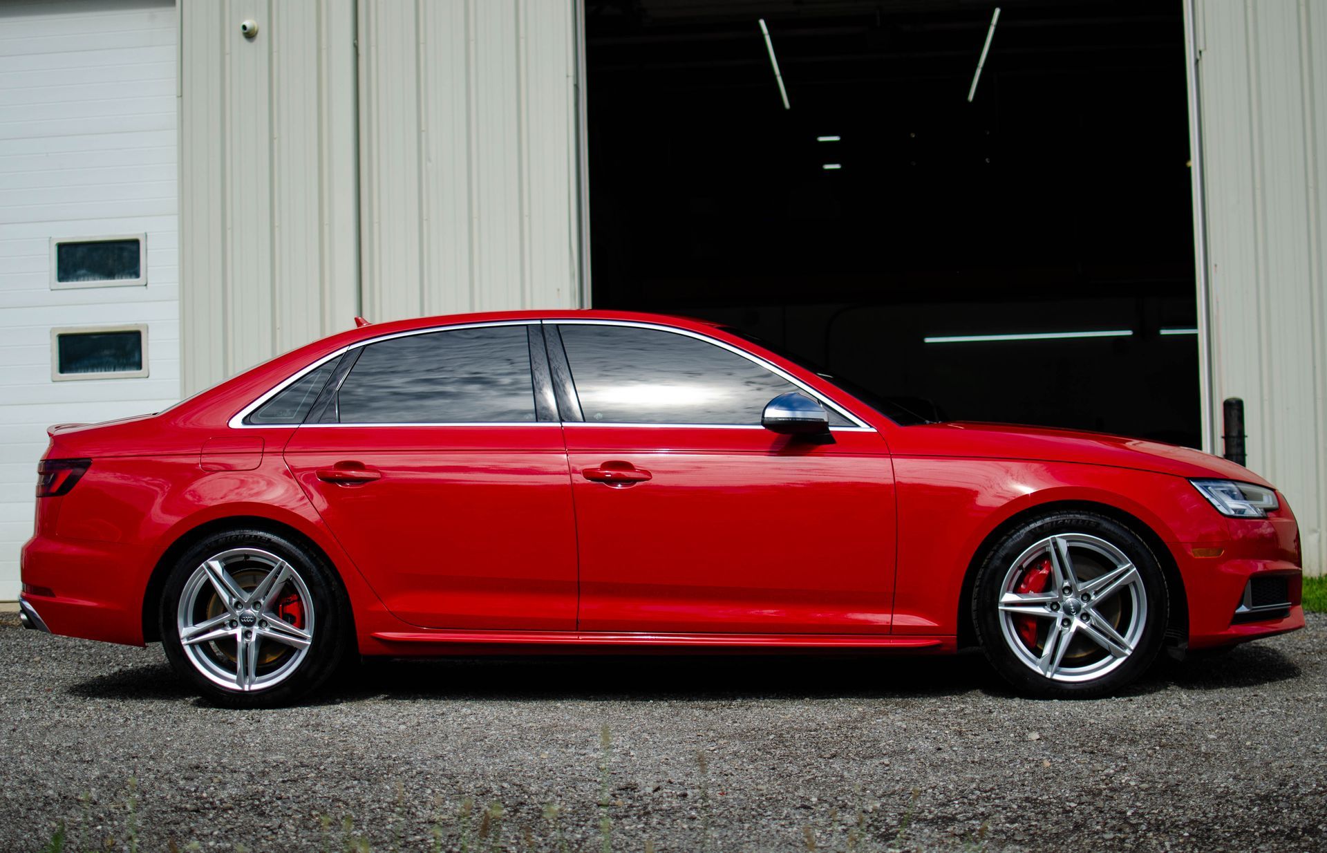 Red sedan parked in front of an open garage door